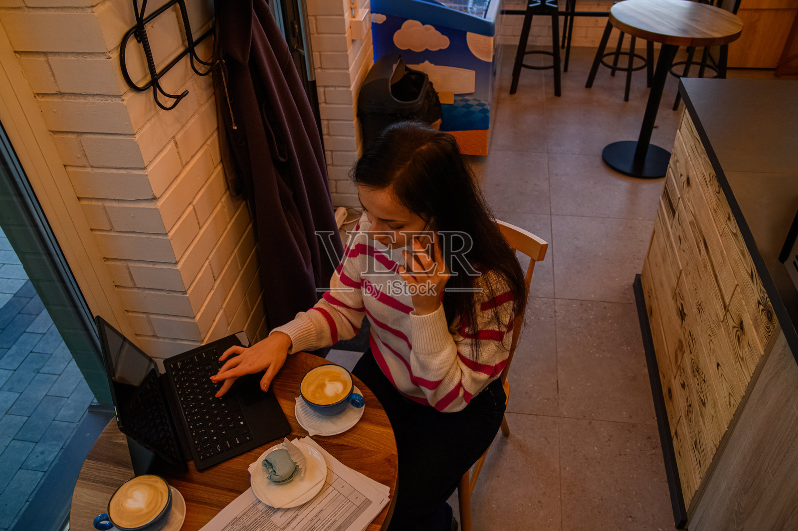 一位女士在舒适的咖啡馆里使用笔记本电脑和咖啡远程工作照片摄影图片