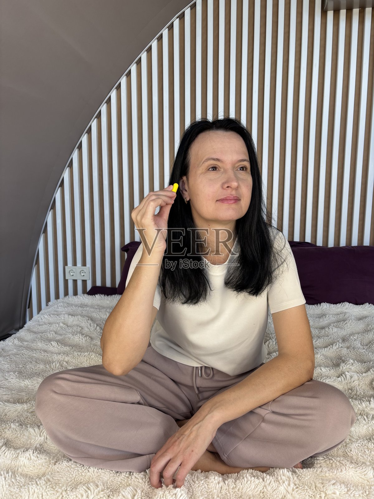 一位平静的棕发女性在家中使用黄色耳塞，以获得更好的睡眠和隔音保护照片摄影图片