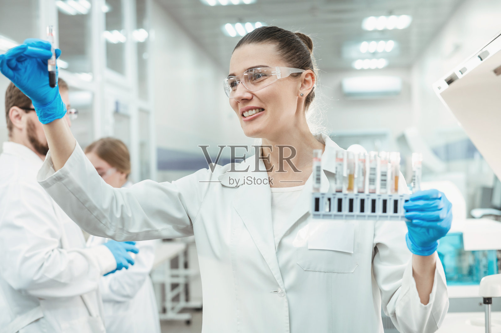 一位女性科学家在设备先进的现代计算机实验室里，使用专用机器分析血液样本和遗传物质照片摄影图片