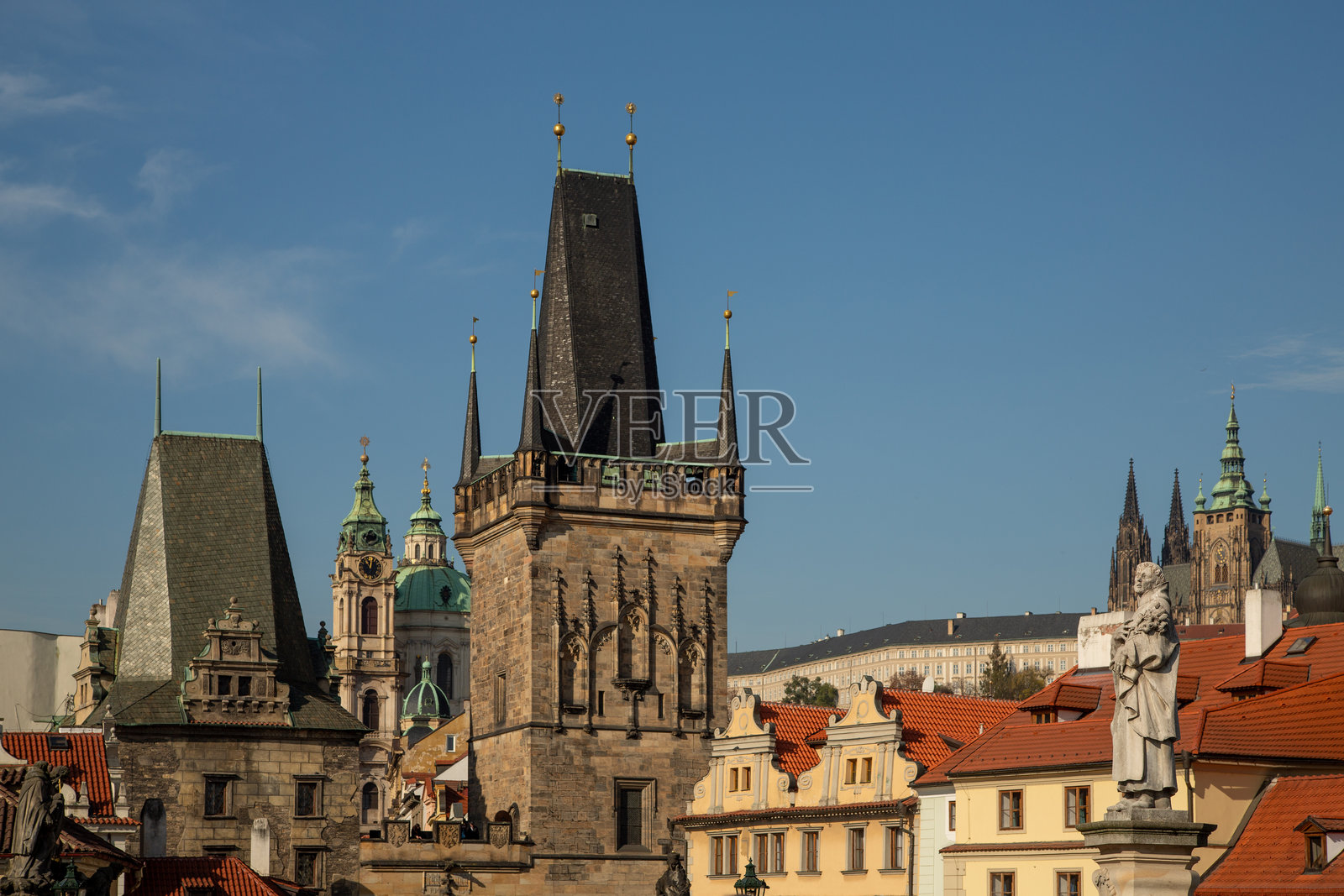 晴朗天气下，布拉格城市景观展示了小城桥塔、查理大桥雕塑和老城区历史建筑，远处可见圣维特大教堂和圣尼古拉教堂。照片摄影图片