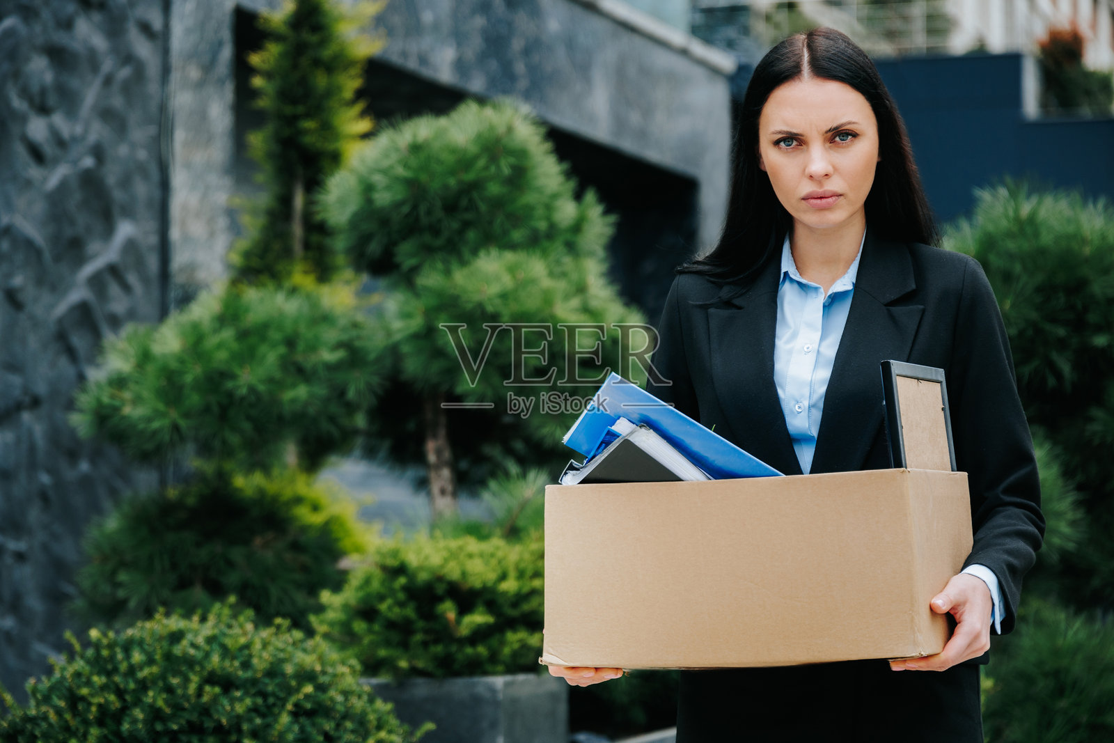 失落的重量：被解雇的女人抱着箱子照片摄影图片