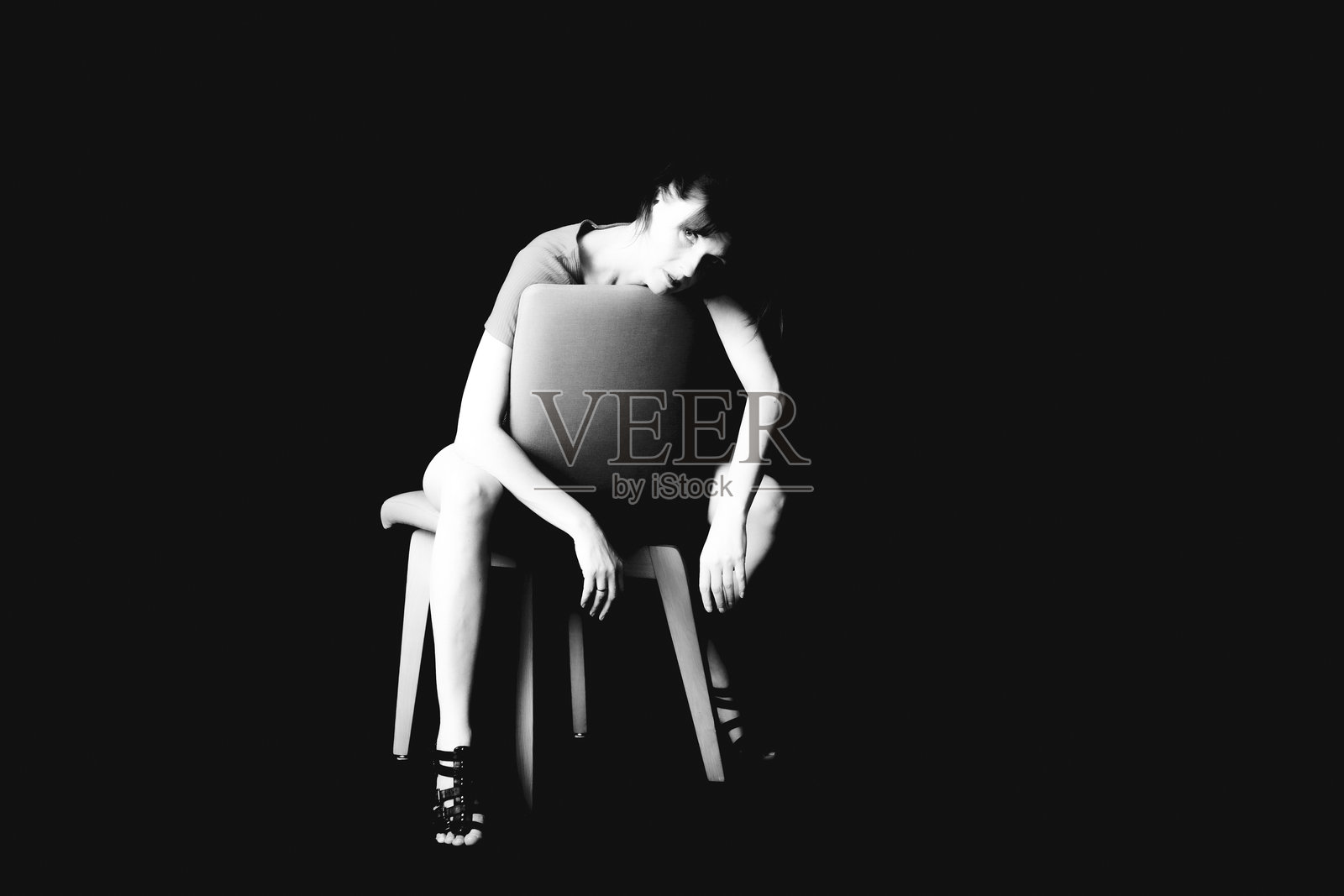 女子背对坐在椅子上，光影戏剧化照片摄影图片