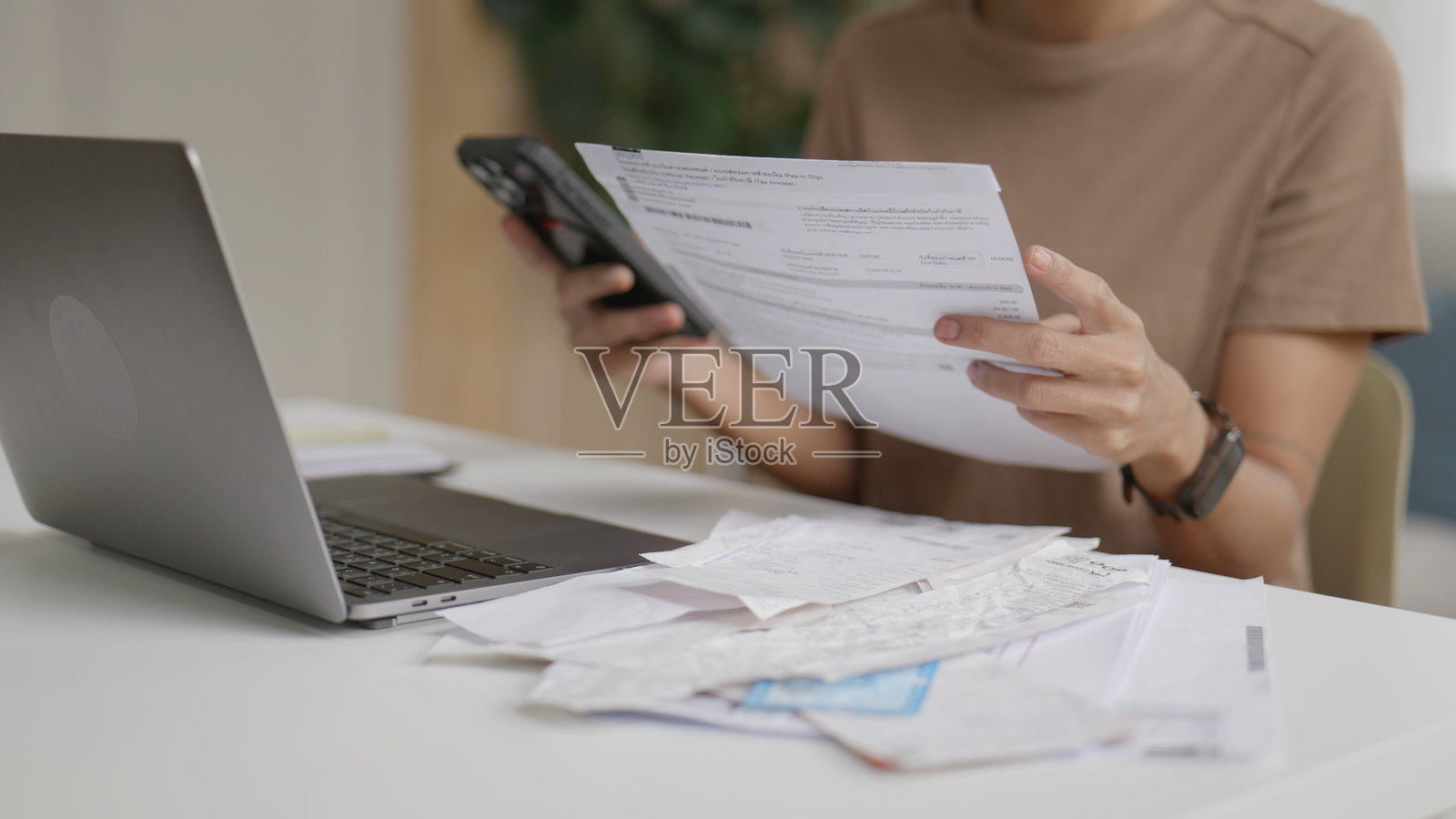 亚洲女性在家中使用智能手机计算支出并在线支付账单。照片摄影图片