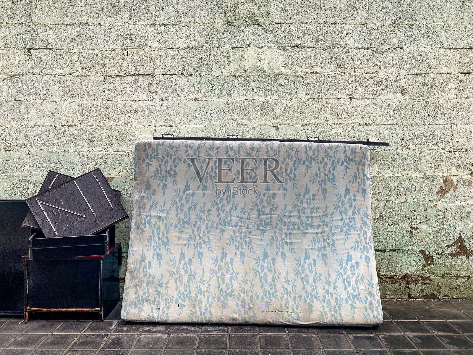 废弃的床垫靠在砖墙上照片摄影图片