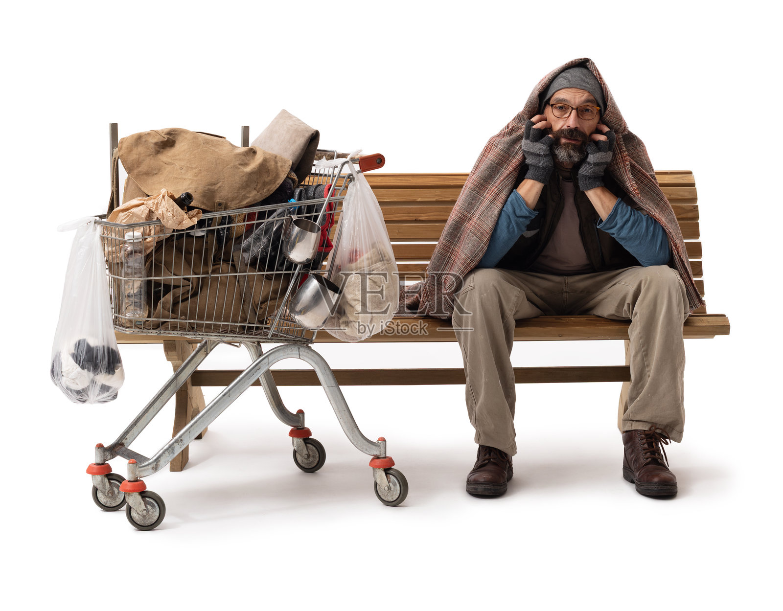 一个无家可归的男人坐在木凳上，旁边放着购物车，纯白背景照片摄影图片