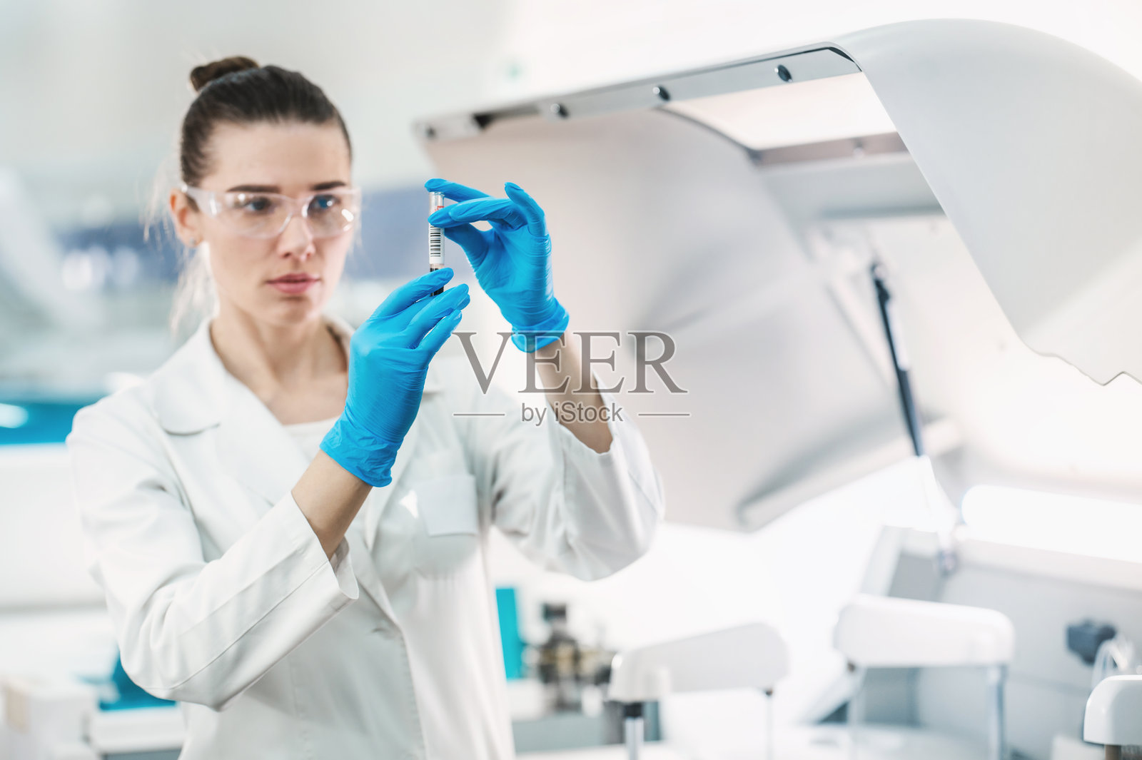 一位女性科研人员在现代生物实验室中，使用试管和移液器进行一系列实验。实验室助理正在做测试。照片摄影图片