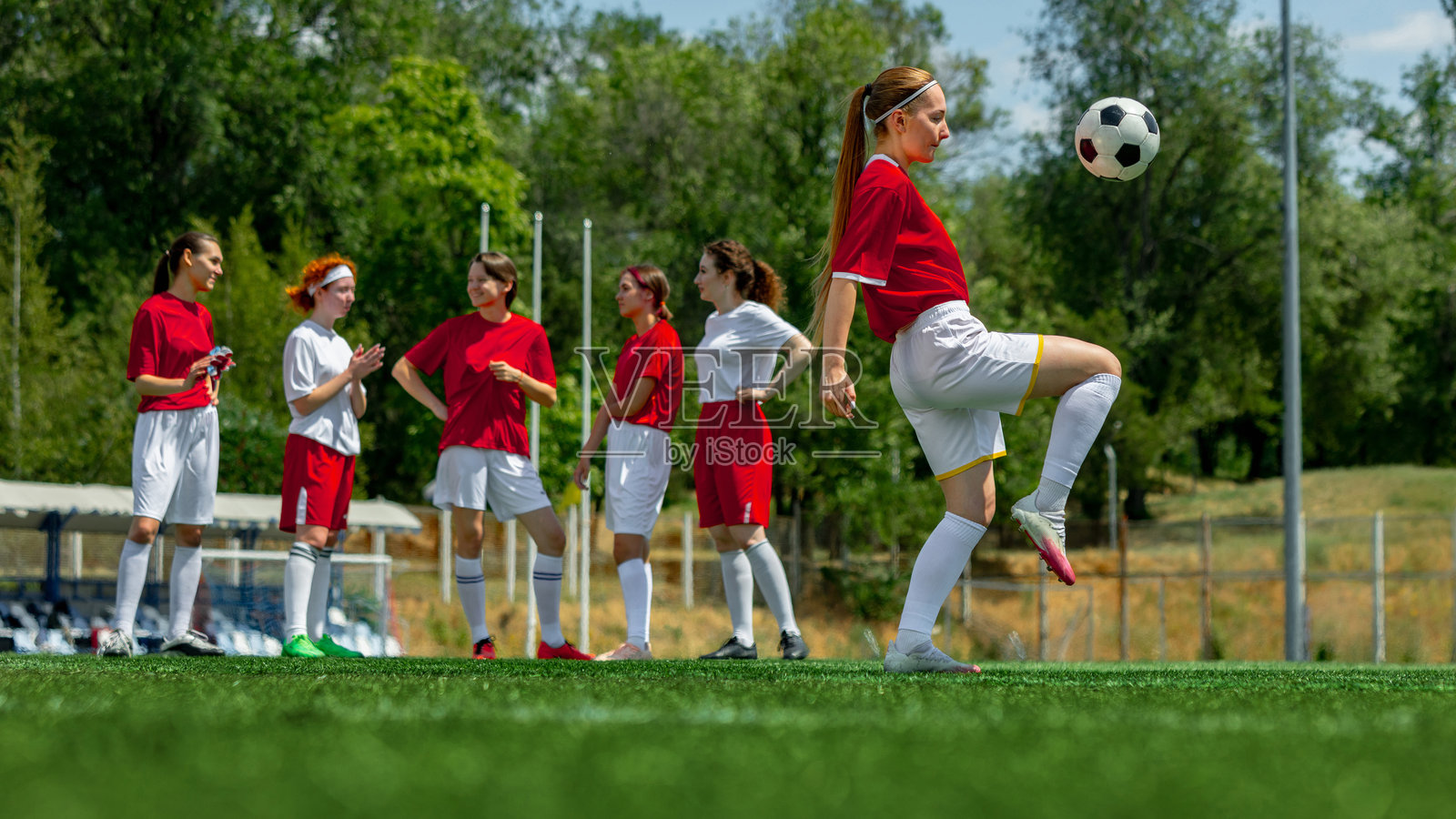 蓝天下的草坪上，女子足球队正在进行训练。照片摄影图片
