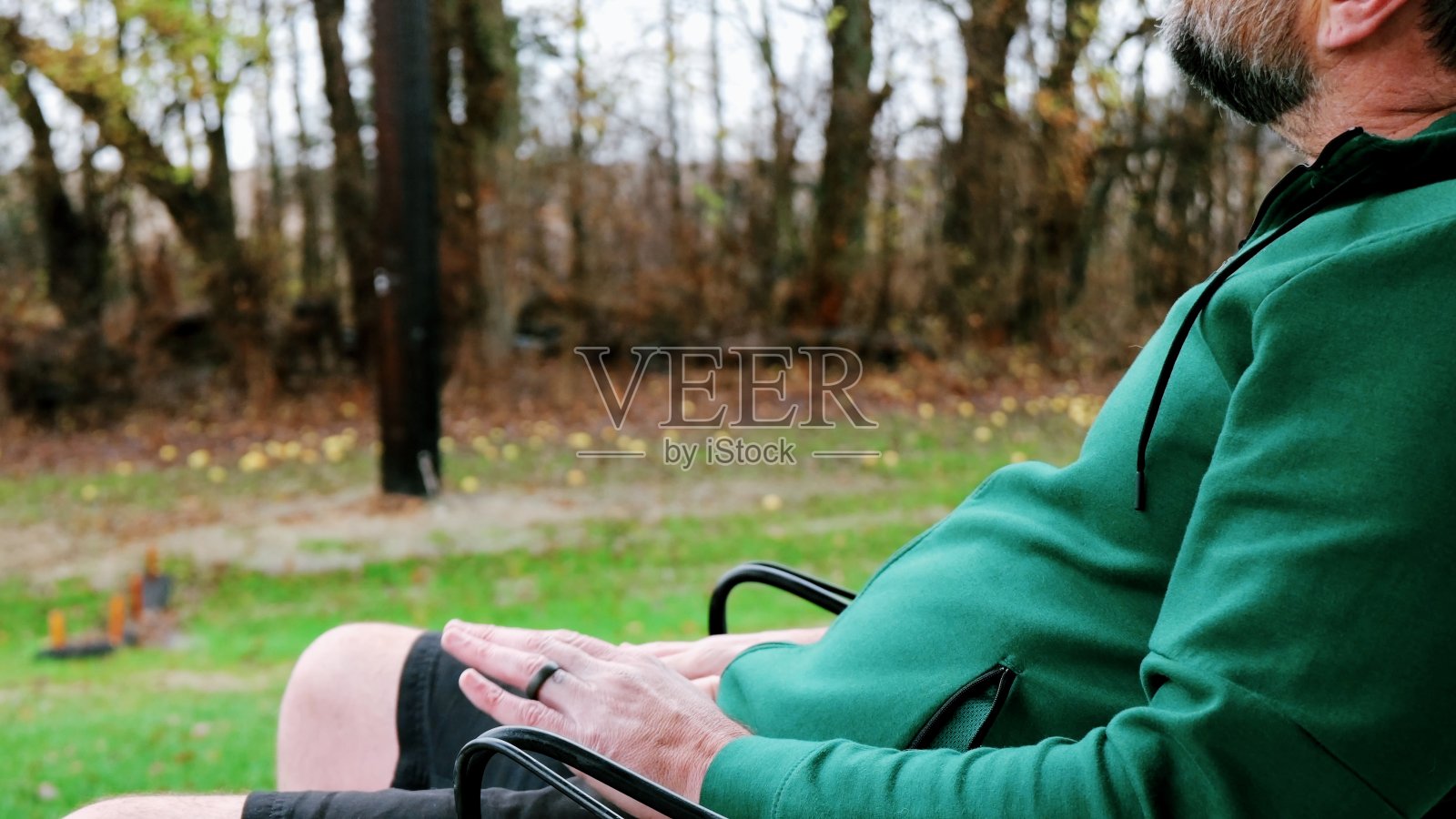 阴郁的一天，一个男人一边看着手机一边四处张望照片摄影图片