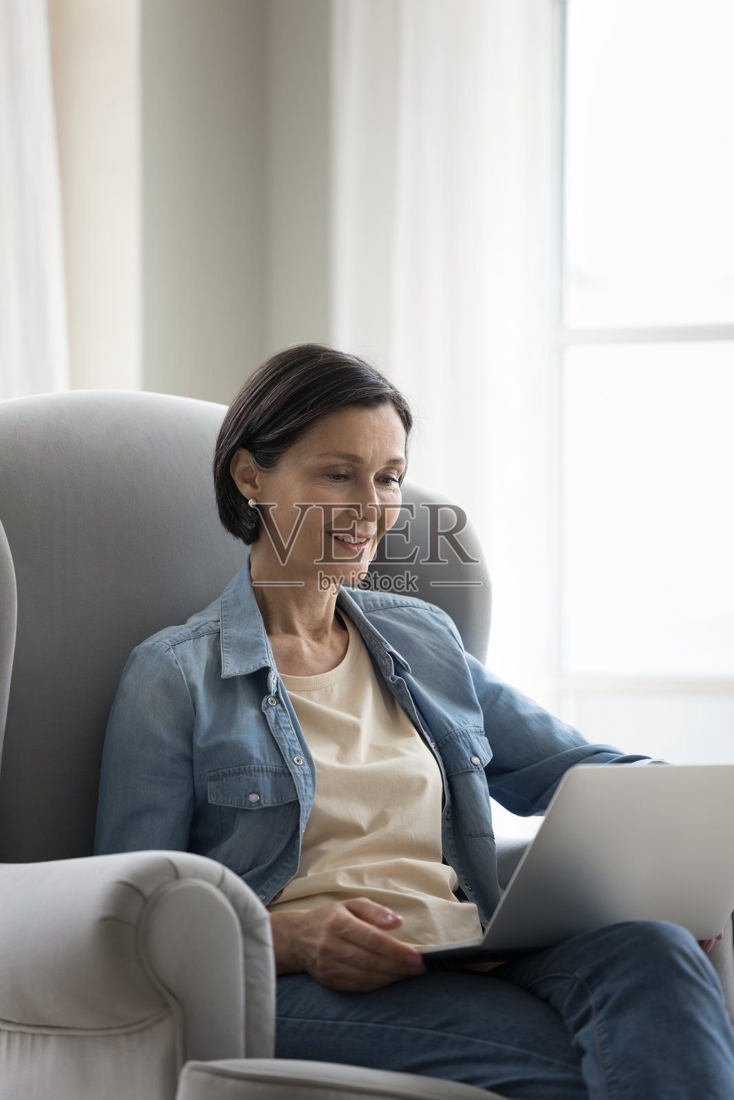 一位对网上新闻感兴趣的中年女性正在用笔记本电脑阅读照片摄影图片