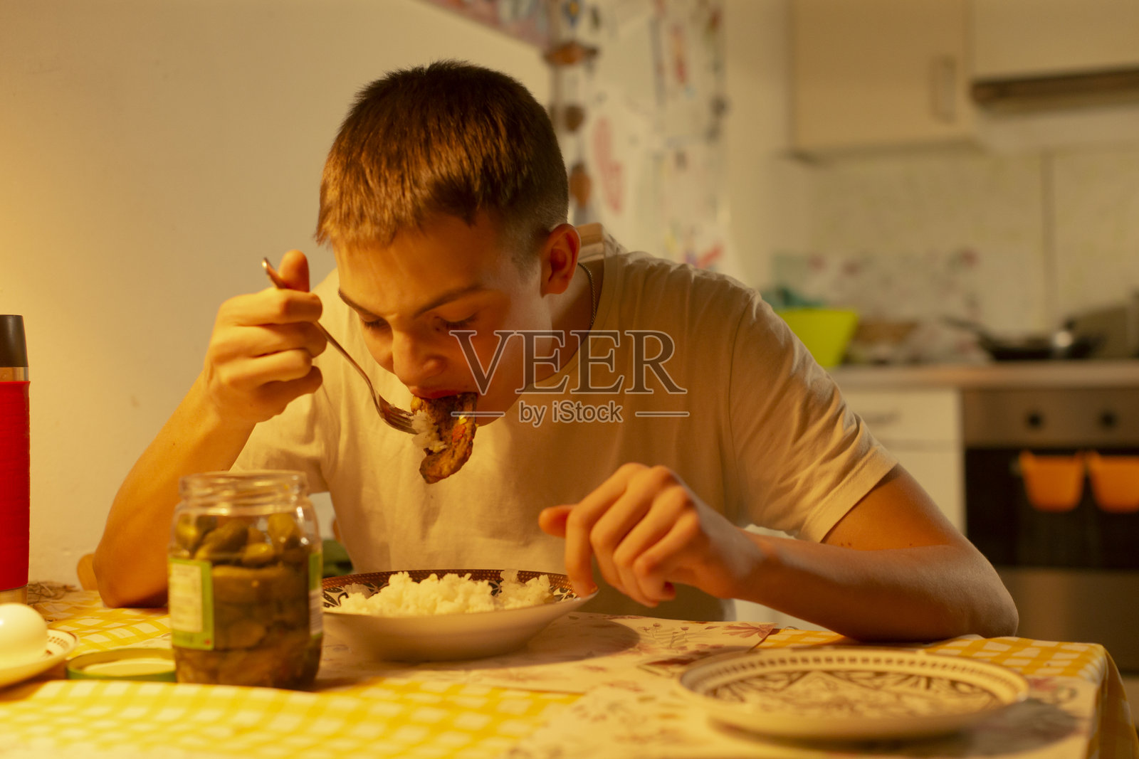 年轻的男学生独自在室内吃着米饭和腌菜的快餐晚餐照片摄影图片