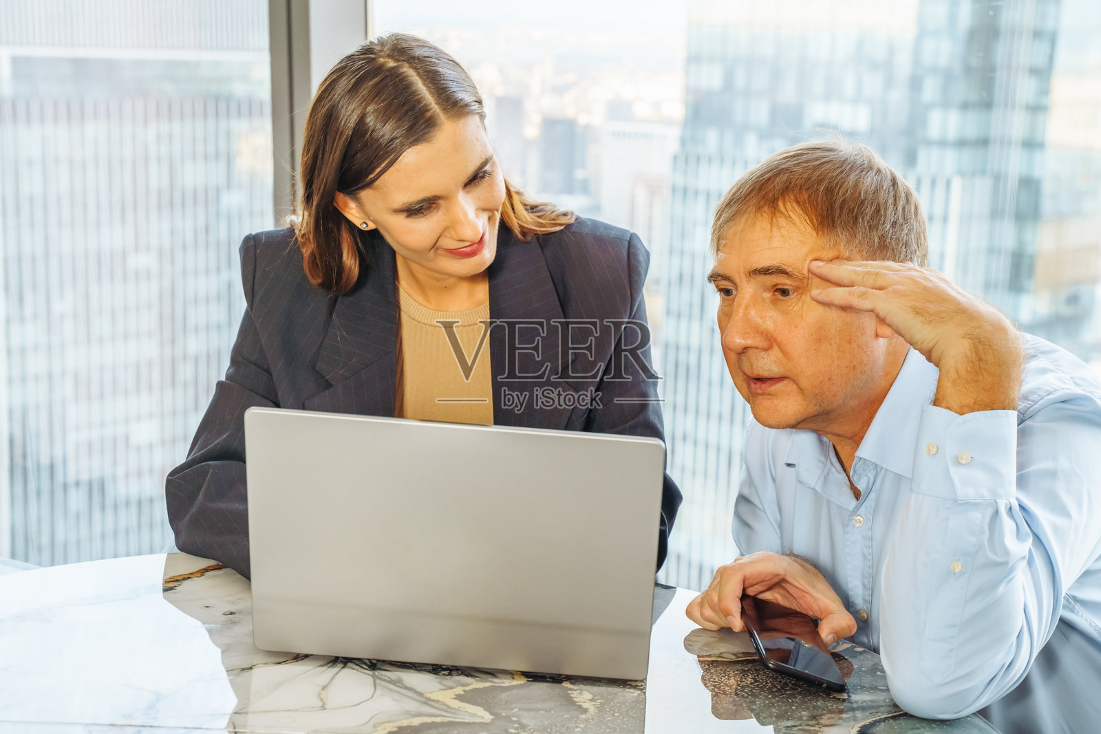 Business professionals discussing strategies while working on a laptop in a modern office照片摄影图片