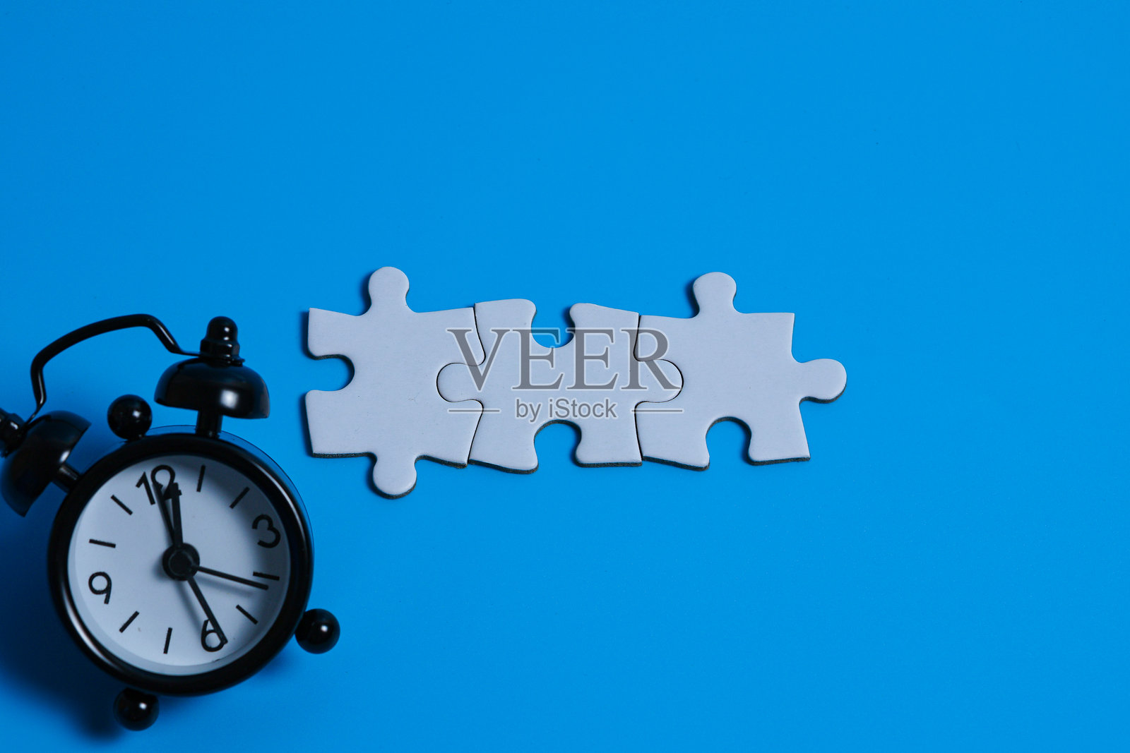 连接的白色拼图块与迷你闹钟照片摄影图片