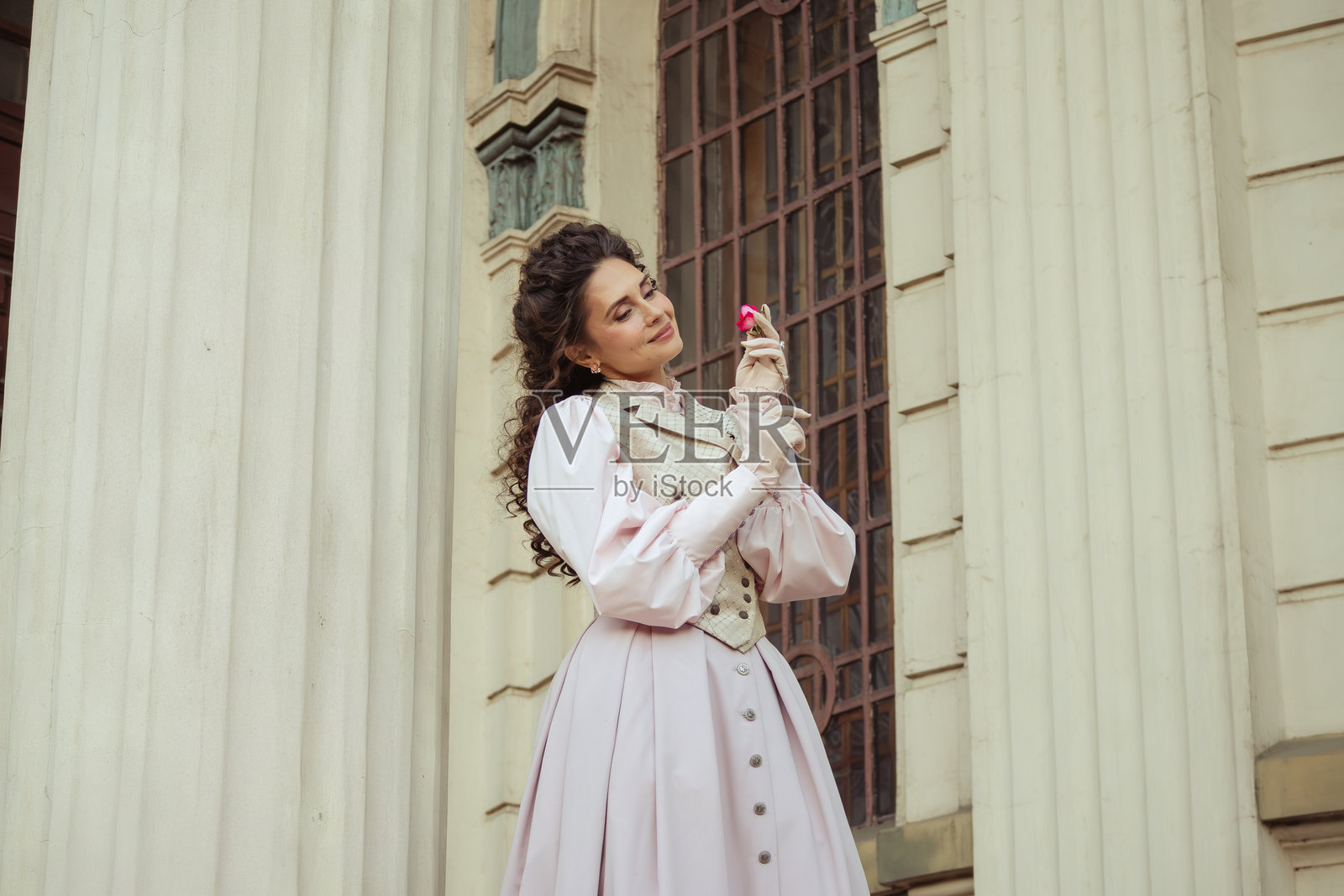 一位女子在古老建筑里拿着一朵玫瑰照片摄影图片