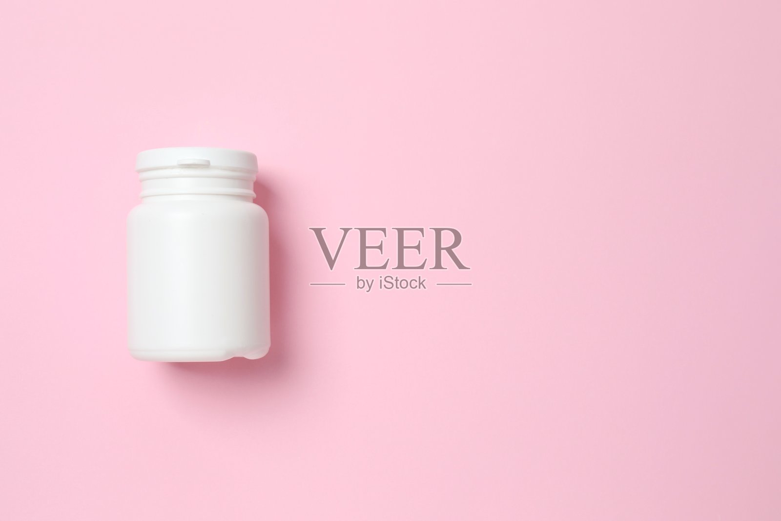 粉色背景上的白色瓶子，俯视角度照片摄影图片