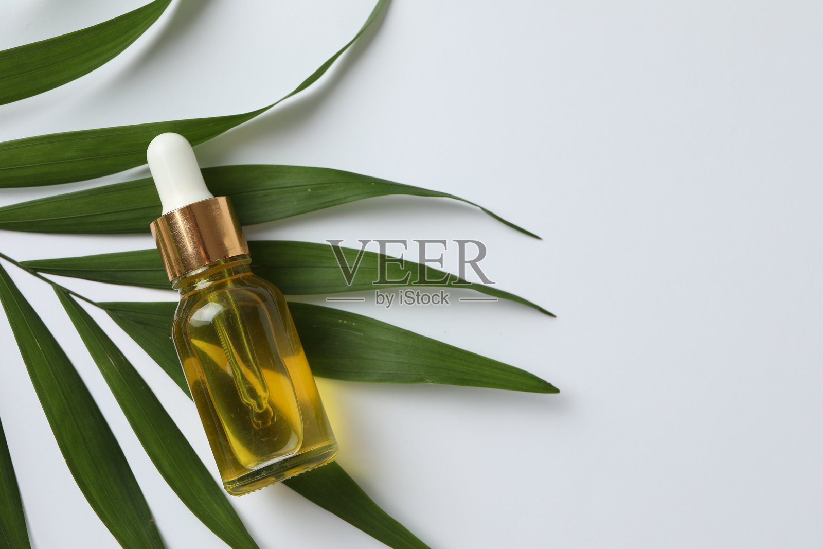 Aromatic essential oils in a glass bottle on the palm leaf. The concept of organic herbal aromatherapy.照片摄影图片