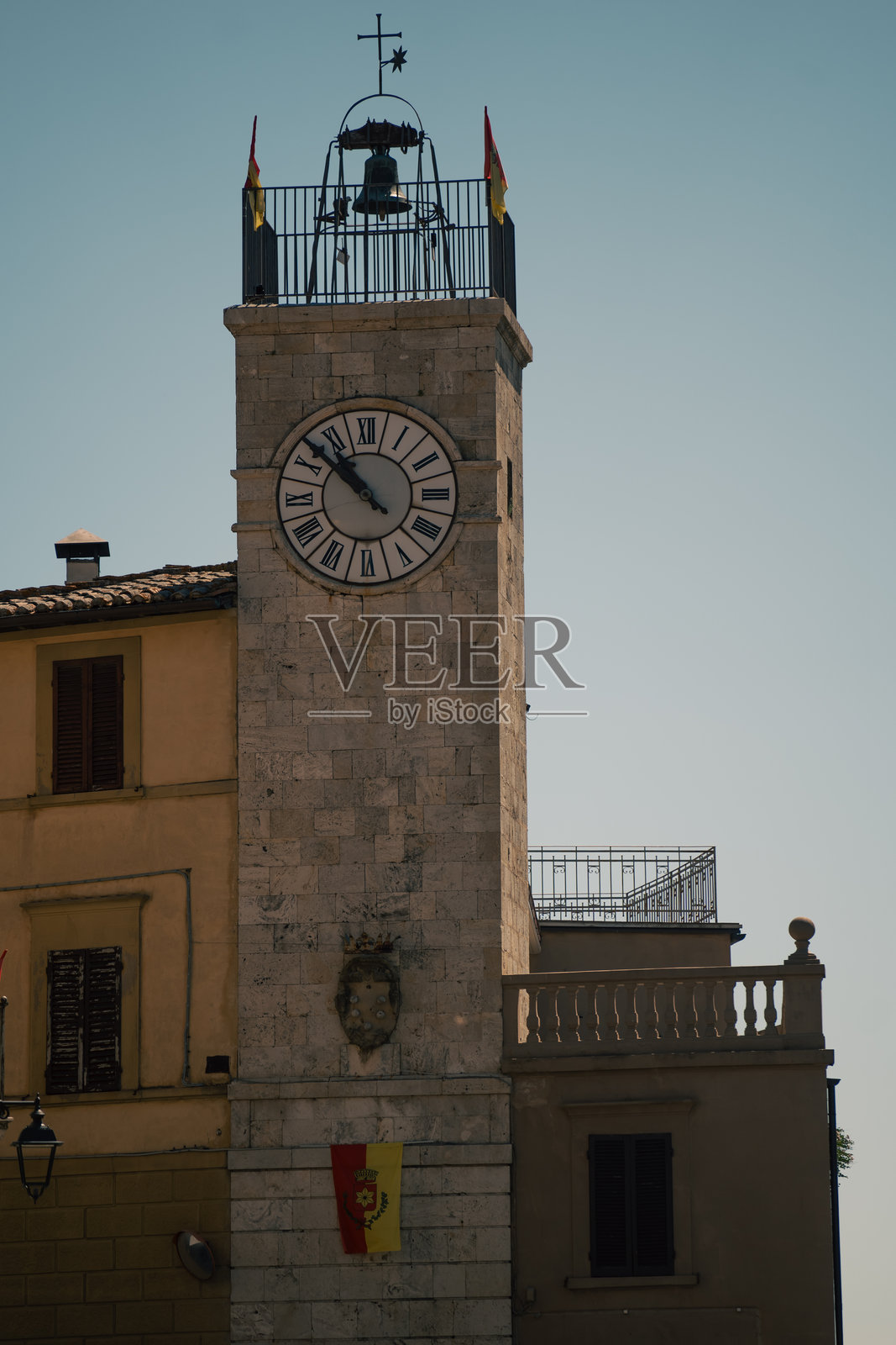 历史悠久的城镇钟楼，垂直拍摄的市政石塔，带有钟表和旗帜，背景是晴朗的天空照片摄影图片
