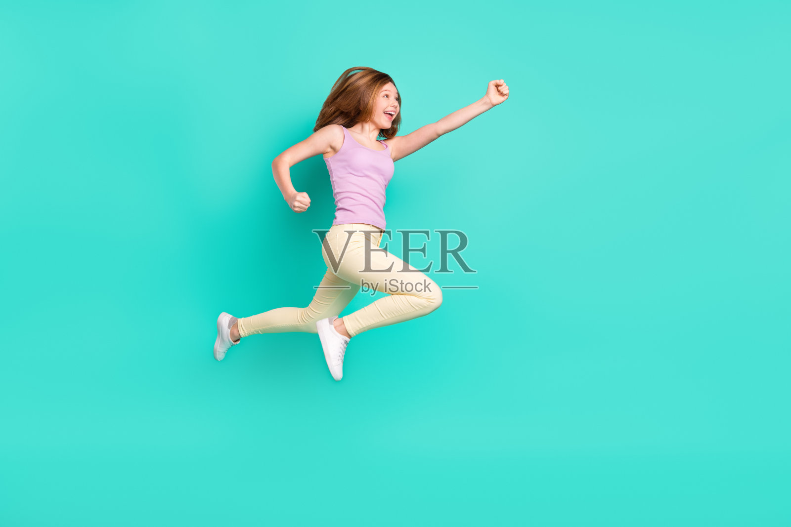 穿着时尚上衣和裤子的时髦棕色小女孩全身侧面照，在蓝绿色背景上孤立照片摄影图片