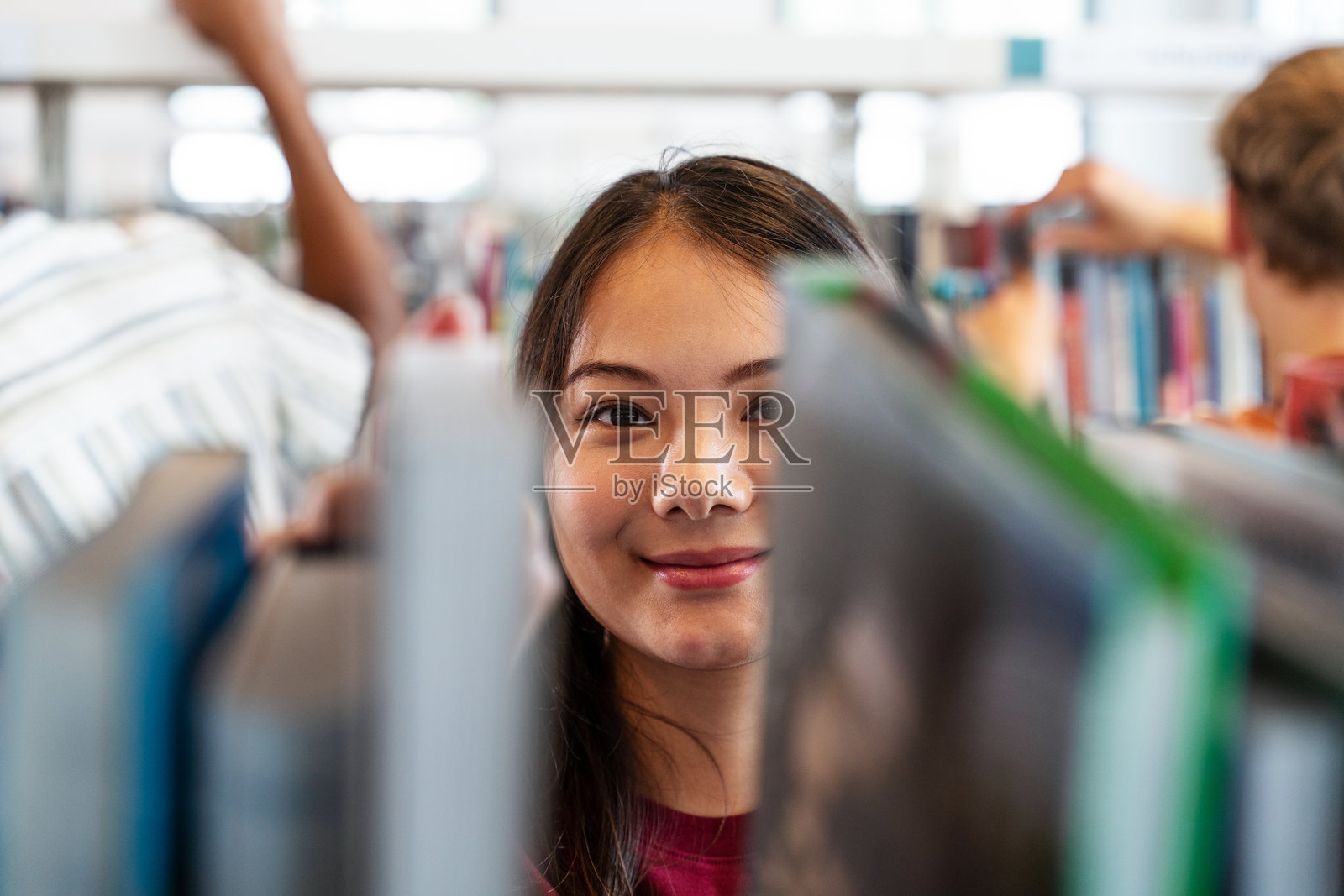一位年轻的中国女性正在图书馆里微笑着翻阅教育类书籍照片摄影图片
