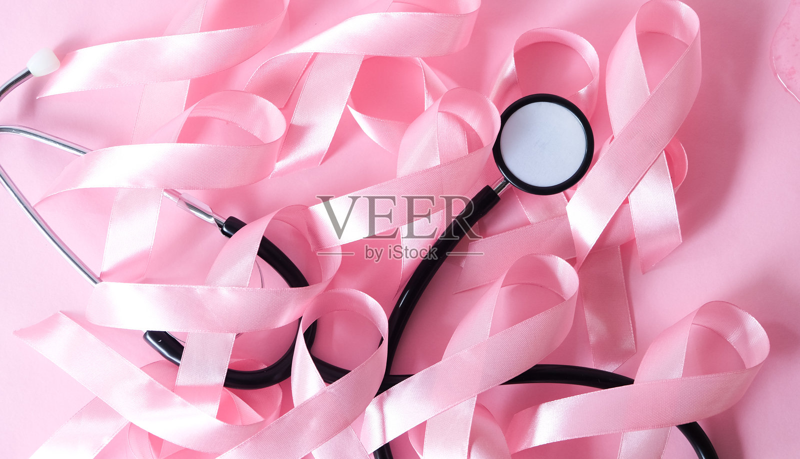 粉色丝带的特写镜头，这是乳腺癌宣传的象征，在粉色背景上孤立。照片摄影图片