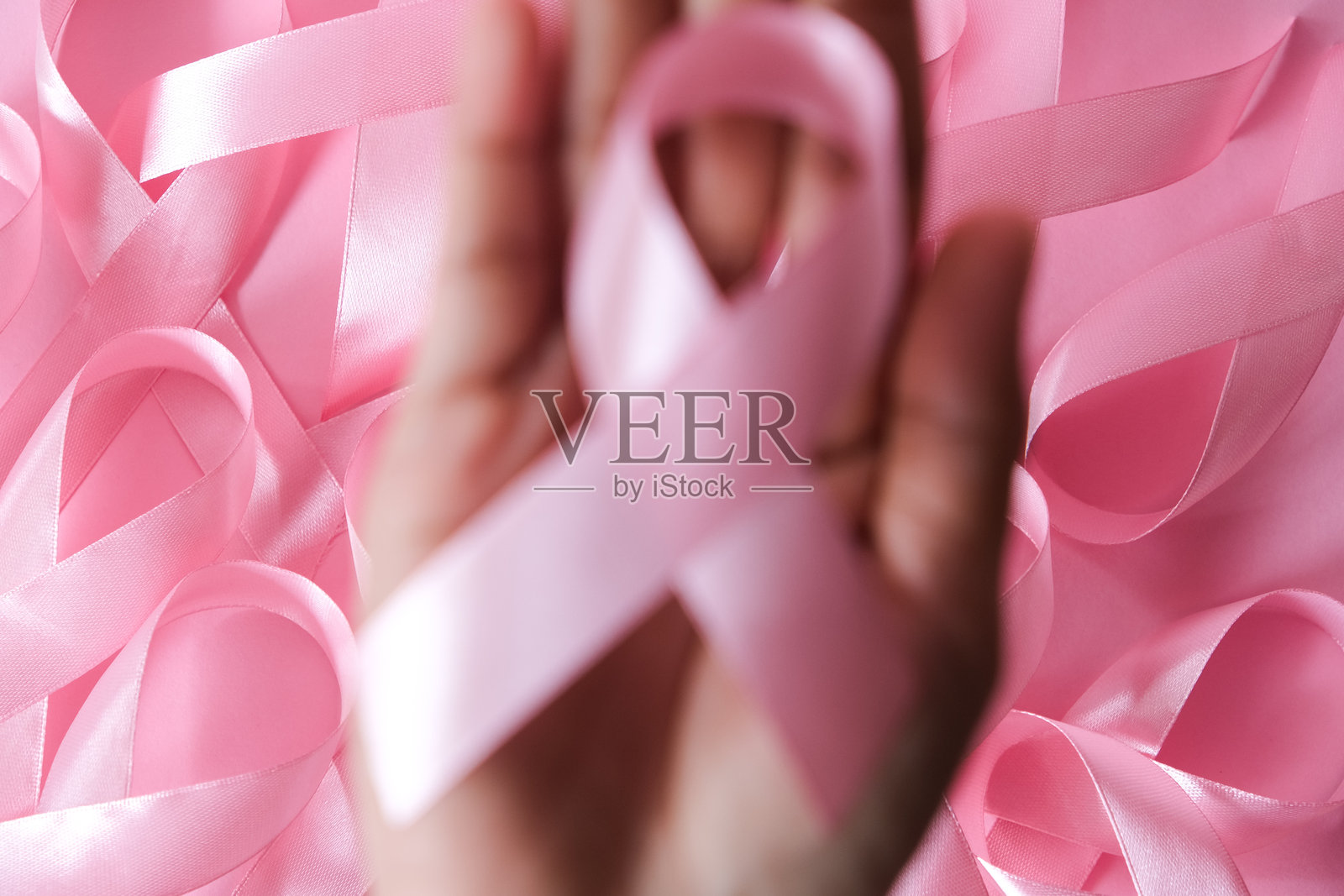 特写一位女士的手，手中握着粉色丝带，象征着对乳腺癌的关注照片摄影图片