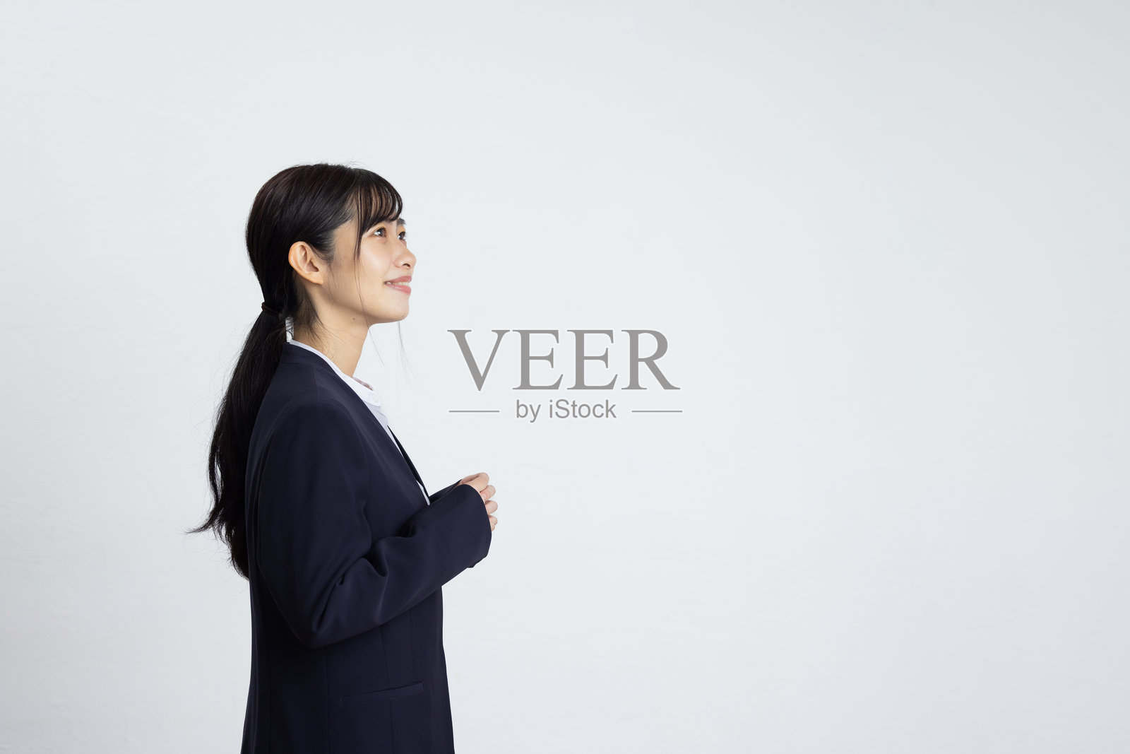 年轻女商人在白色墙壁前的侧面肖像，面带微笑照片摄影图片