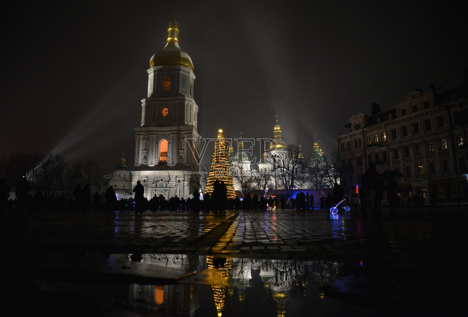 圣索菲亚大教堂在灯光的照耀下，以及旁边明亮的圣诞树和它们在水坑中的倒影照片摄影图片