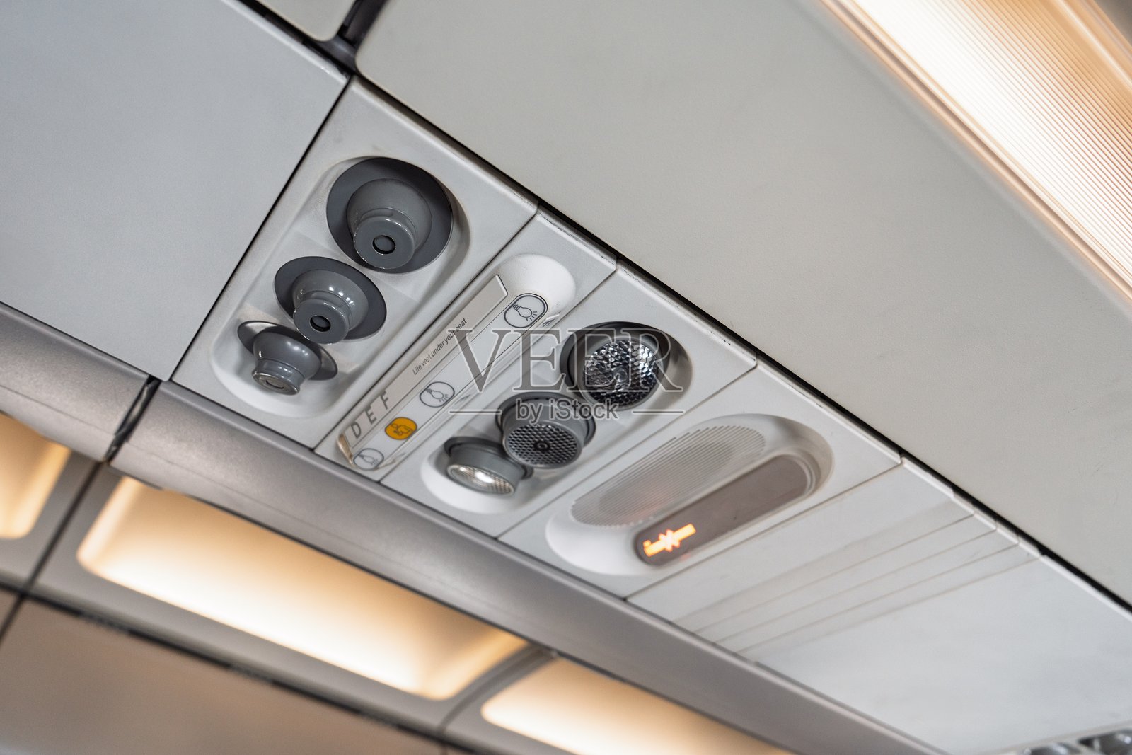 飞机上的顶置控制台，配有空调出风口、阅读灯和呼叫按钮，提供旅行舒适体验照片摄影图片