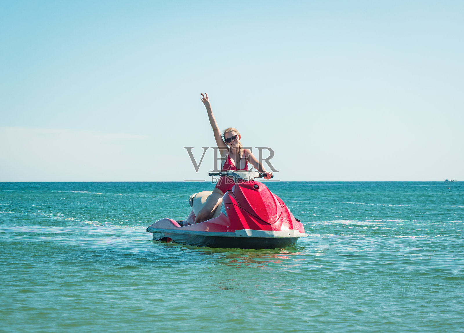 一位女士在热带海滩附近，在清澈蔚蓝的海水中享受阳光明媚的喷气滑雪时光照片摄影图片