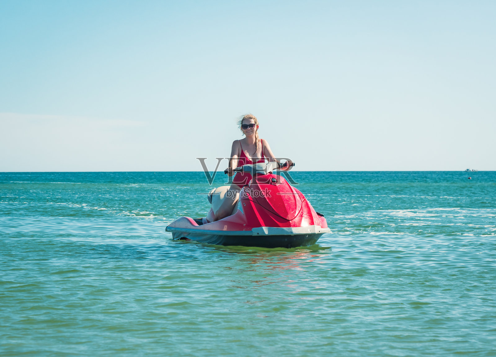 一位女士在热带海滩附近，在清澈湛蓝的海水中享受阳光明媚的喷气滑雪时光照片摄影图片