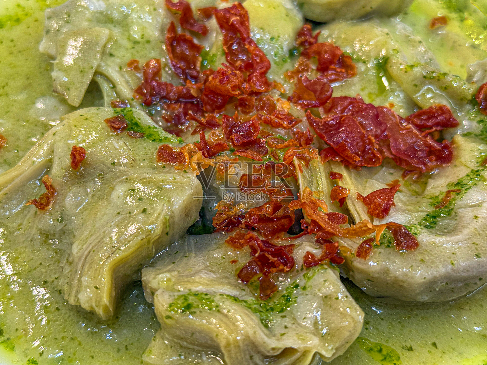 绿酱（萨尔萨酱）炖朝鲜蓟心配酥脆火腿碎。传统西班牙蔬菜小吃菜肴特写。照片摄影图片