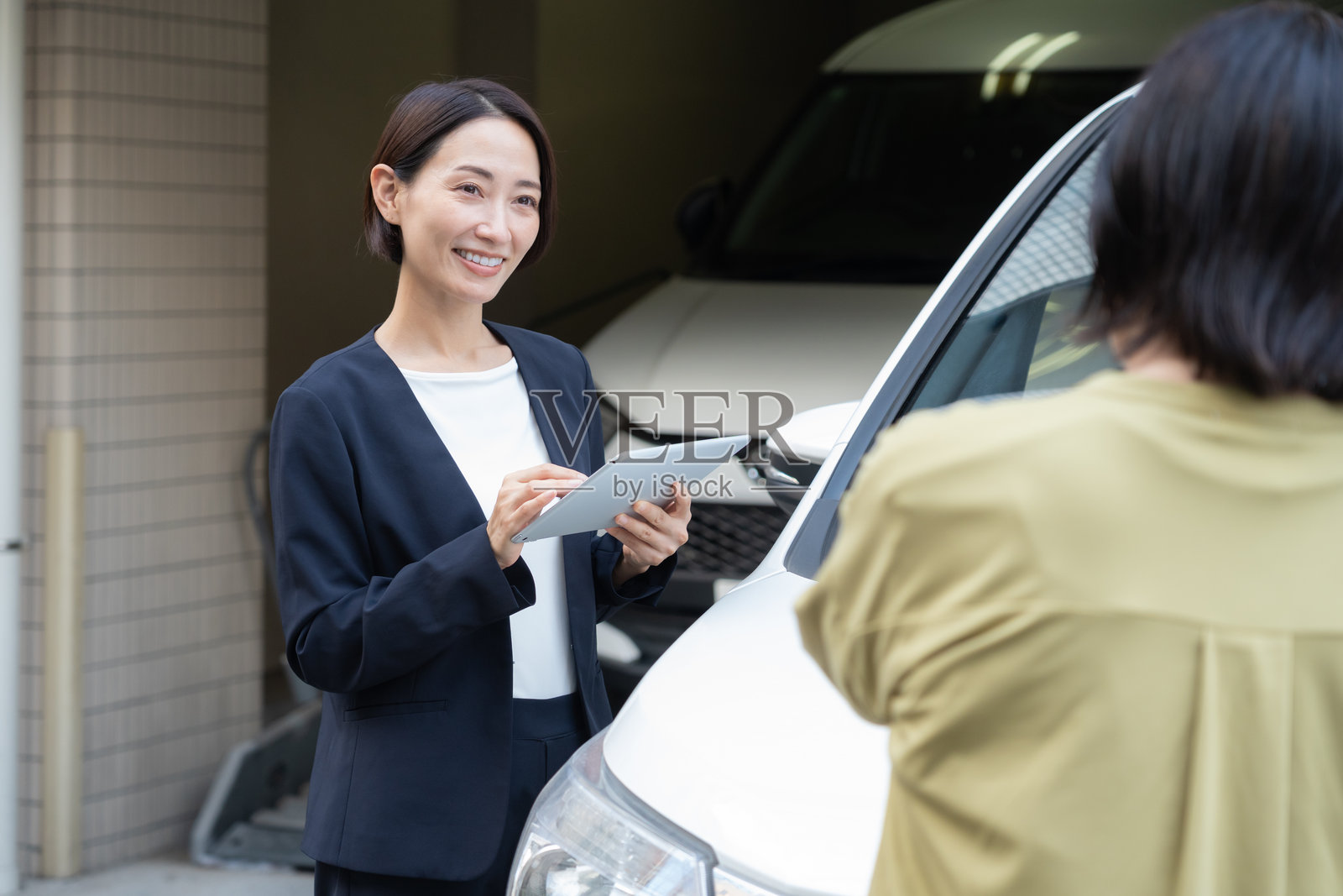 一位中年女商人正在评估一辆汽车照片摄影图片