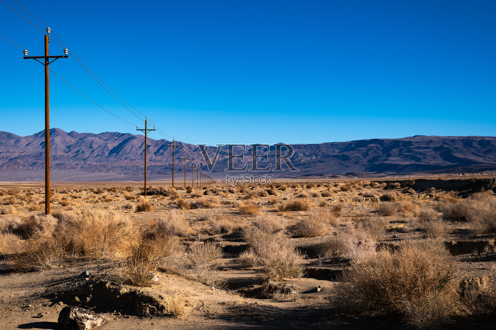 背景是沙漠山脉和丘陵的电线杆线照片摄影图片