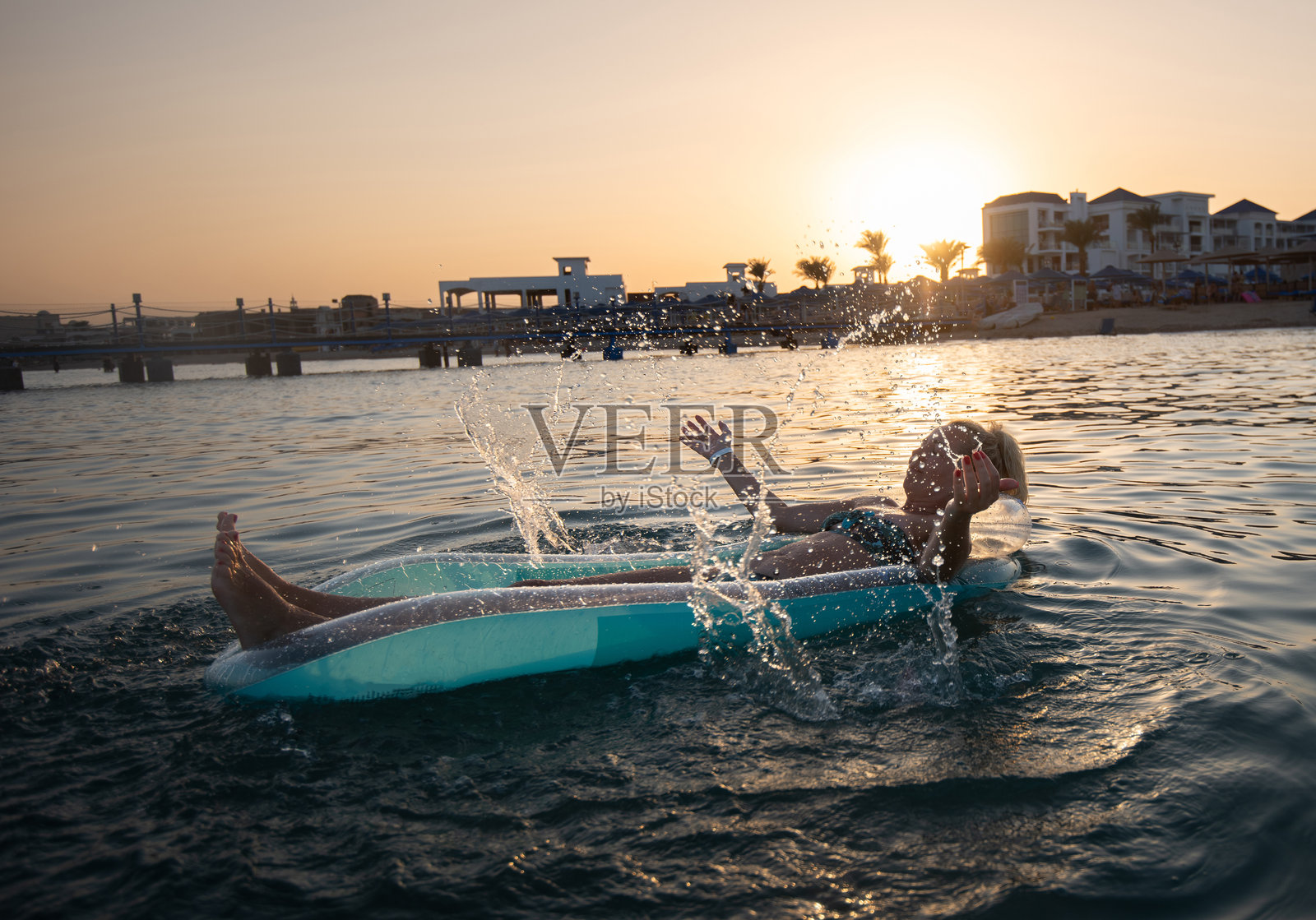 女子在充气筏上漂浮，享受夏日假期。照片摄影图片