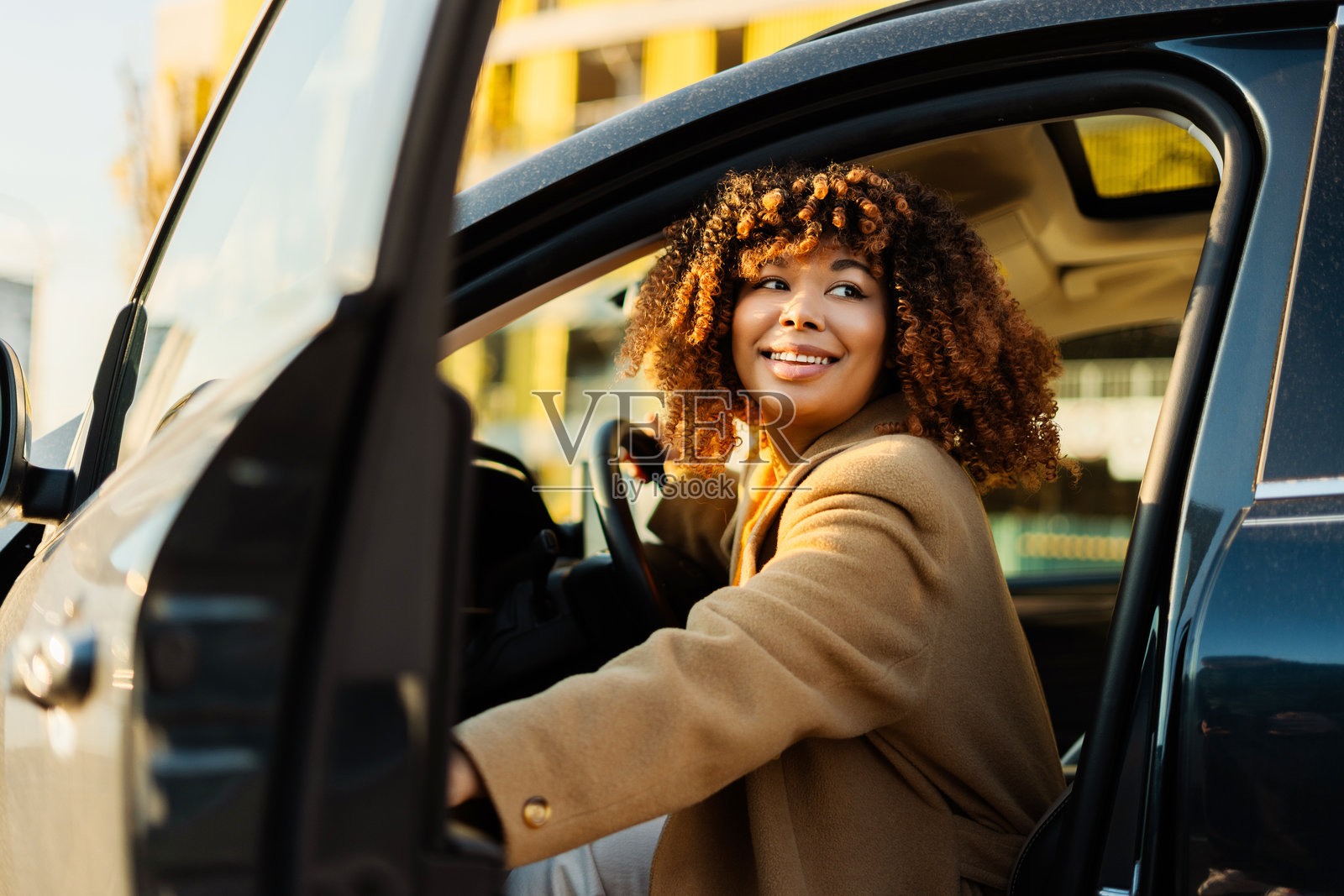 快乐的黑人女性进入汽车，面带微笑，感受都市的自由与独立照片摄影图片