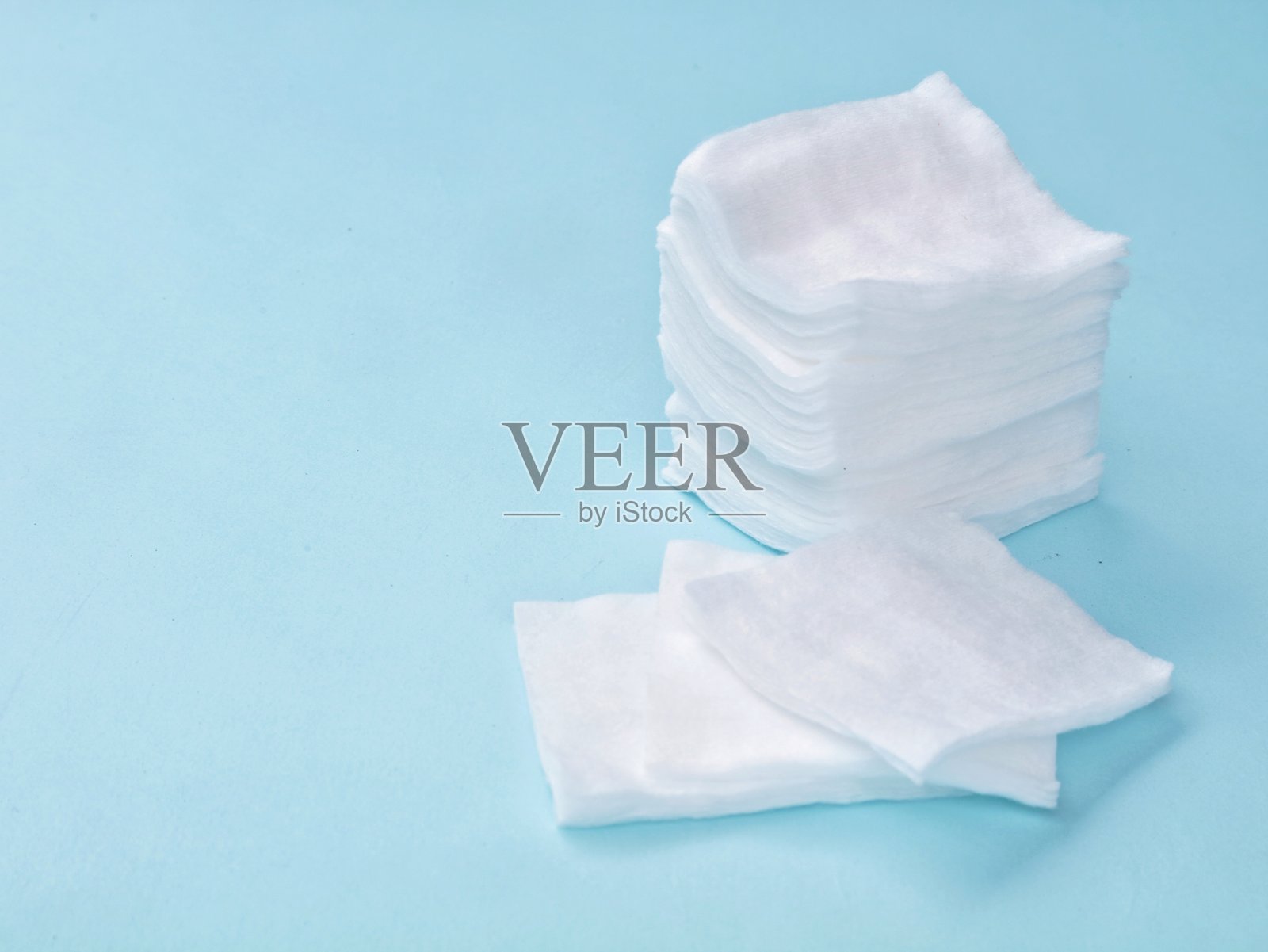 浅蓝色背景上的白色化妆棉堆照片摄影图片