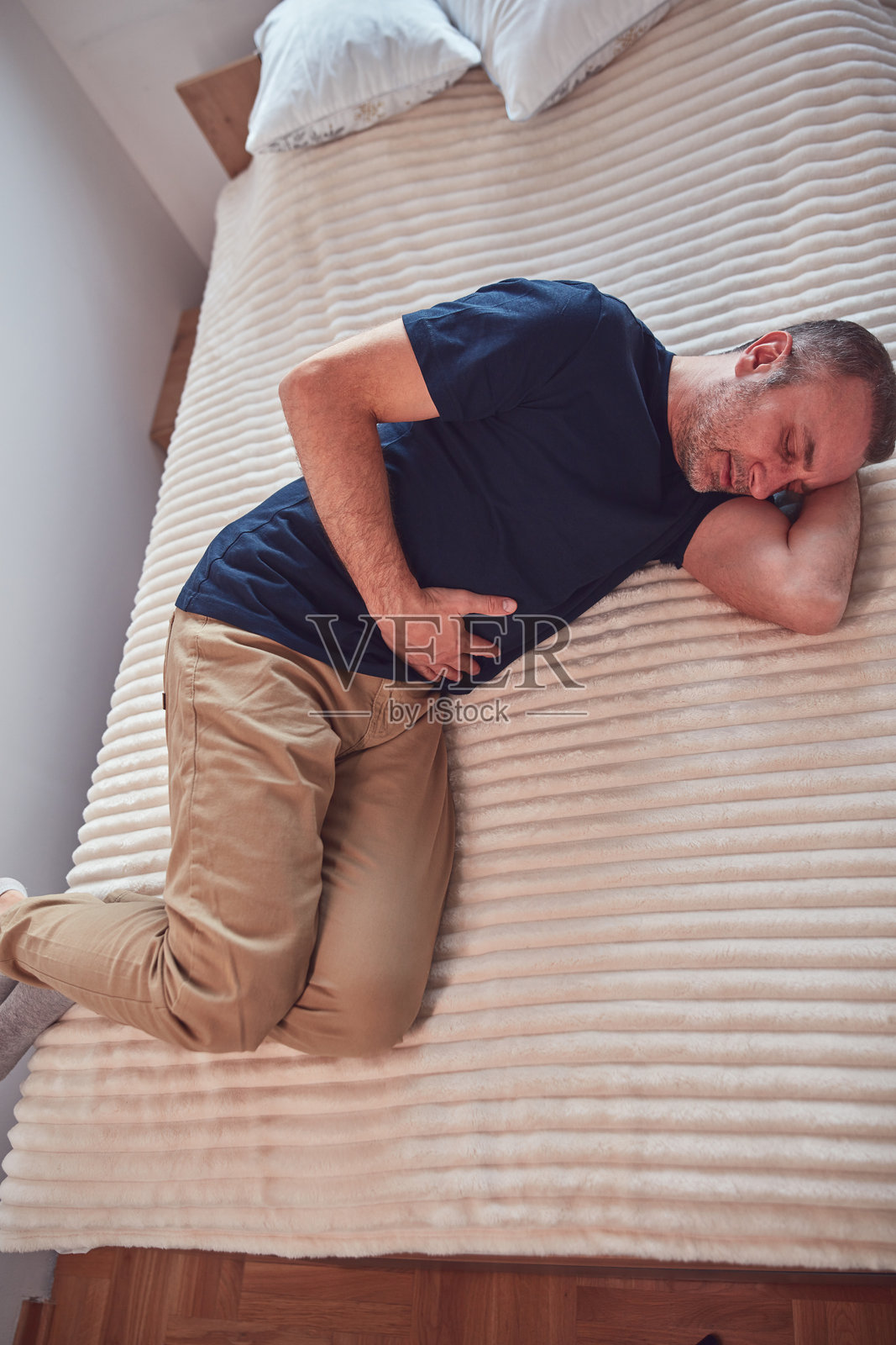 患有胃病的男子在家中感到胸部、胃部和腹部疼痛。照片摄影图片