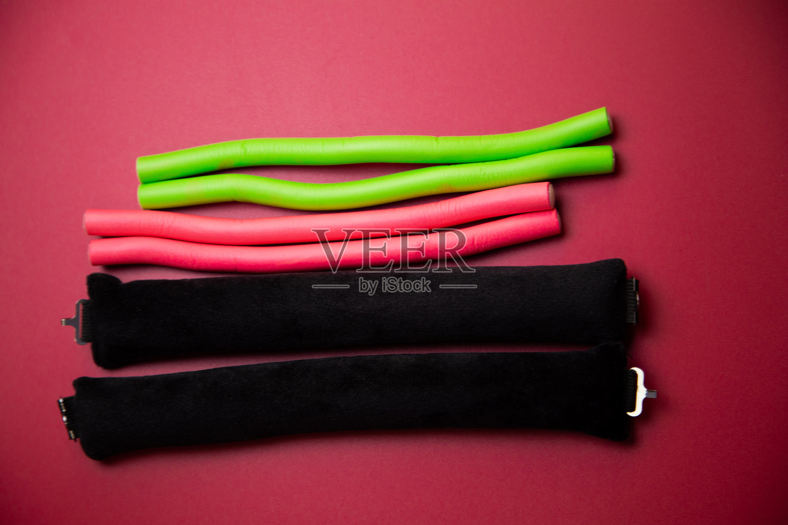 粉色背景下，卷发器特写，长而可弯曲，用于打造丰盈的发型和卷发。发型、蓬松、卷发和自我护理的概念。照片摄影图片