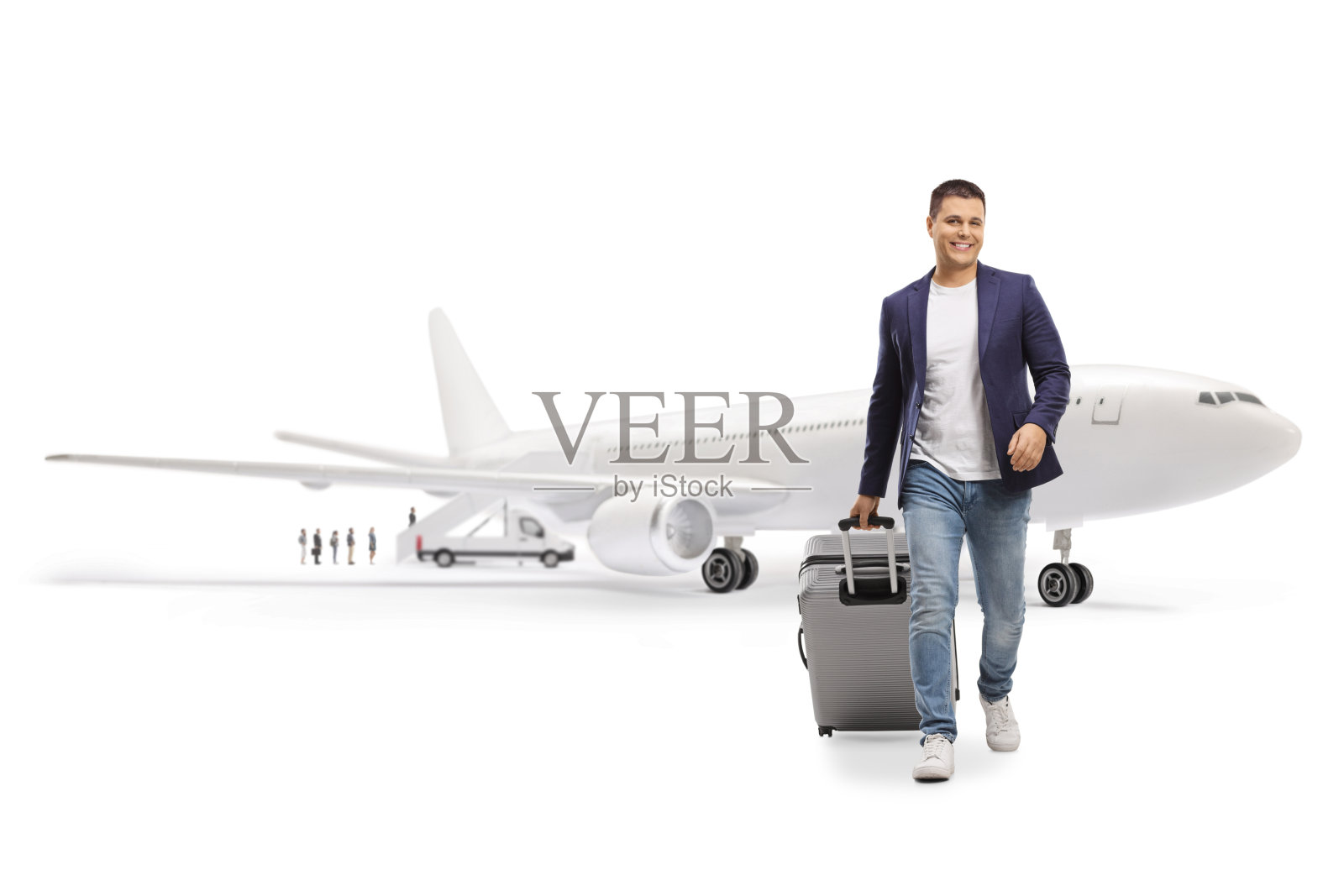 一名男子在机场面带微笑，手提行李箱走向镜头的全身肖像照片摄影图片