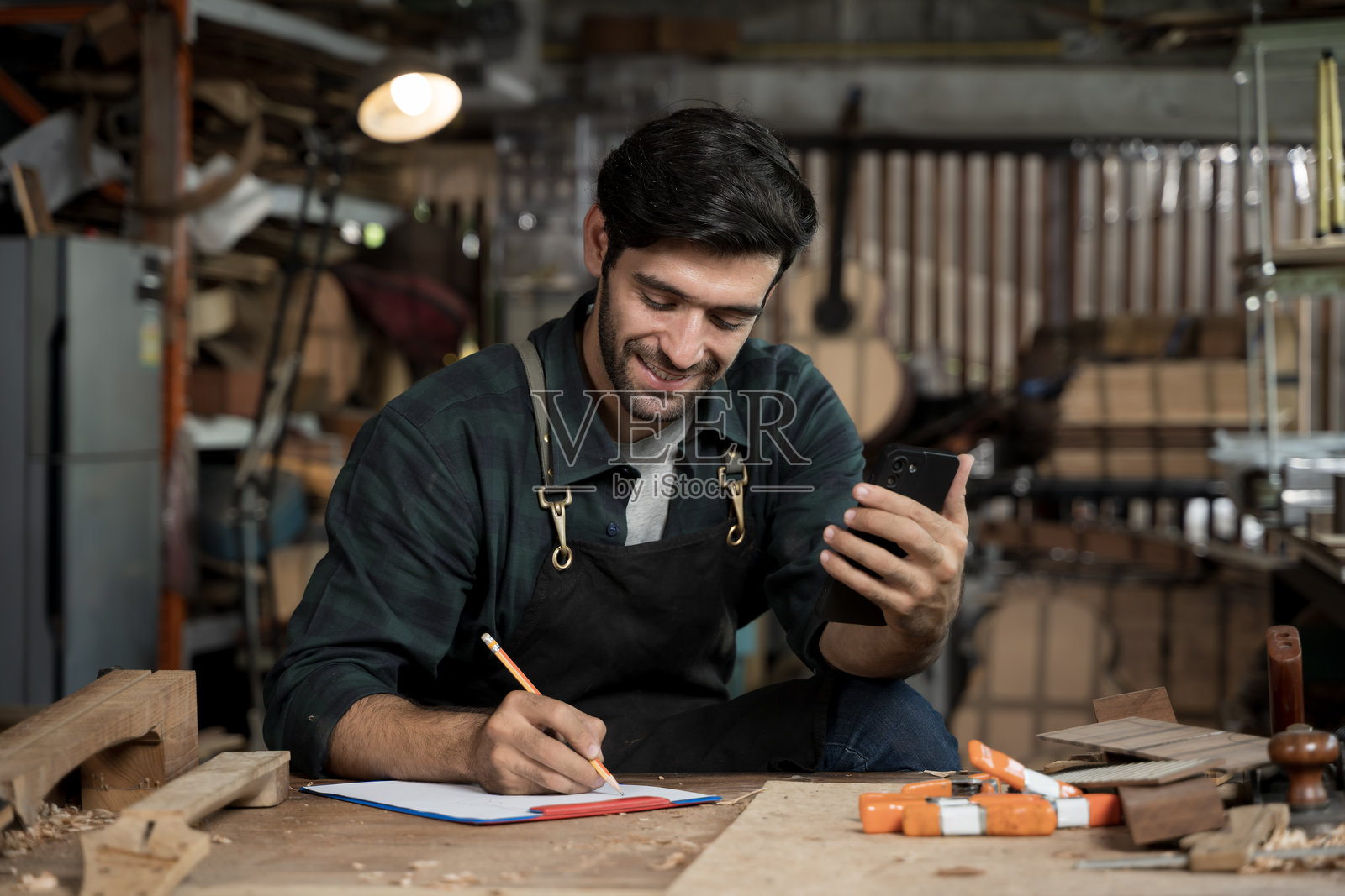 木匠在木工车间使用智能手机并记录笔记照片摄影图片