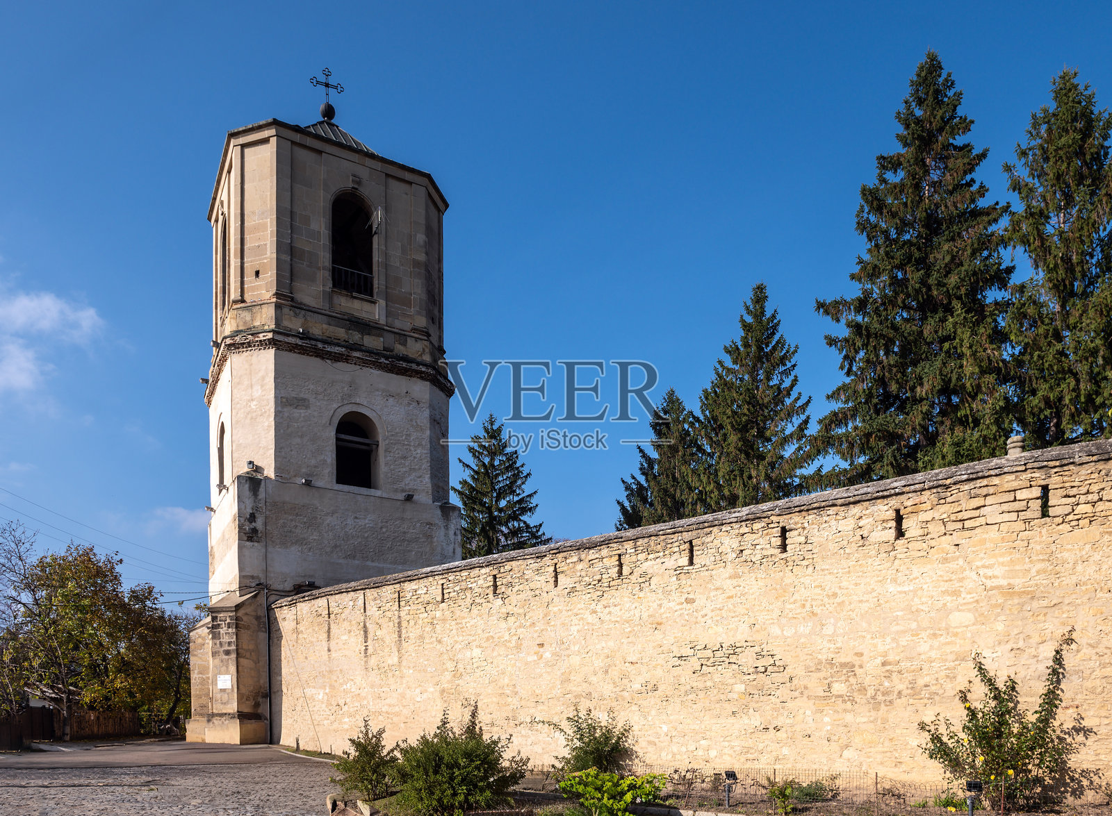 蓝色天空下的历史悠久的加拉太修道院钟楼和石墙照片摄影图片
