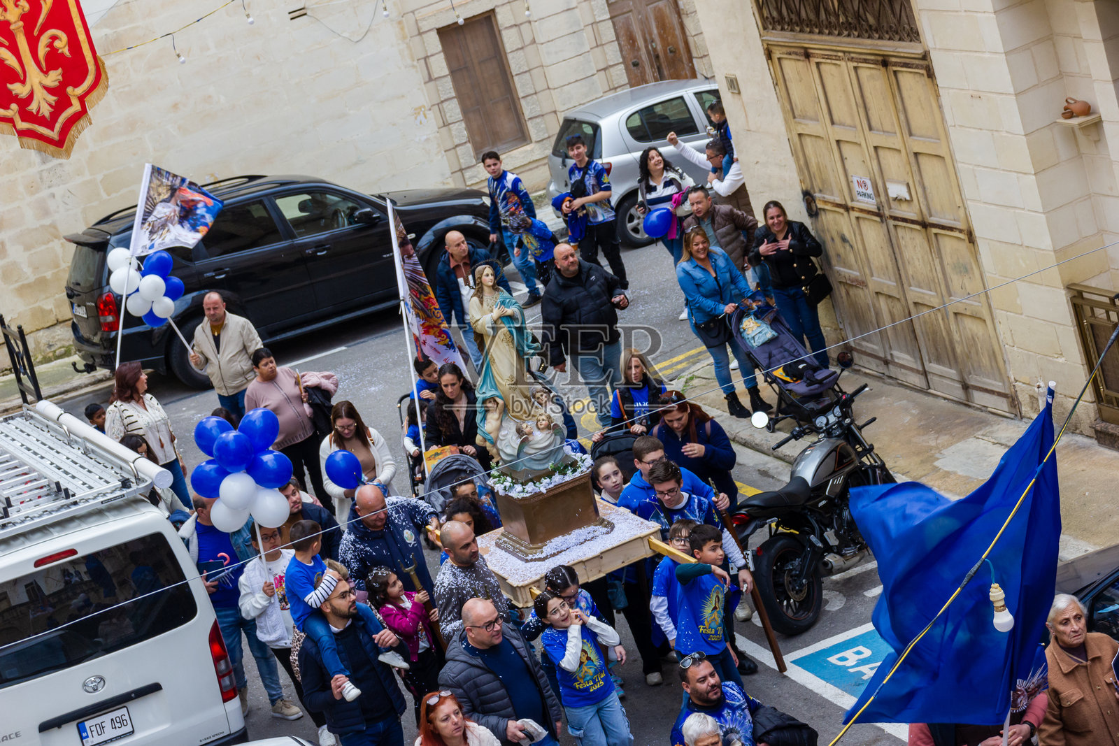 宗教街头游行，人群身着蓝色服饰，伴有圣母玛利亚雕像和节日横幅照片摄影图片