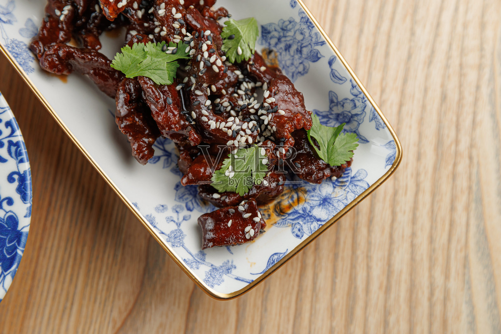 用装饰碗盛放的切片肉菜，配有香草和芝麻，突显了融合多种风味的特色照片摄影图片