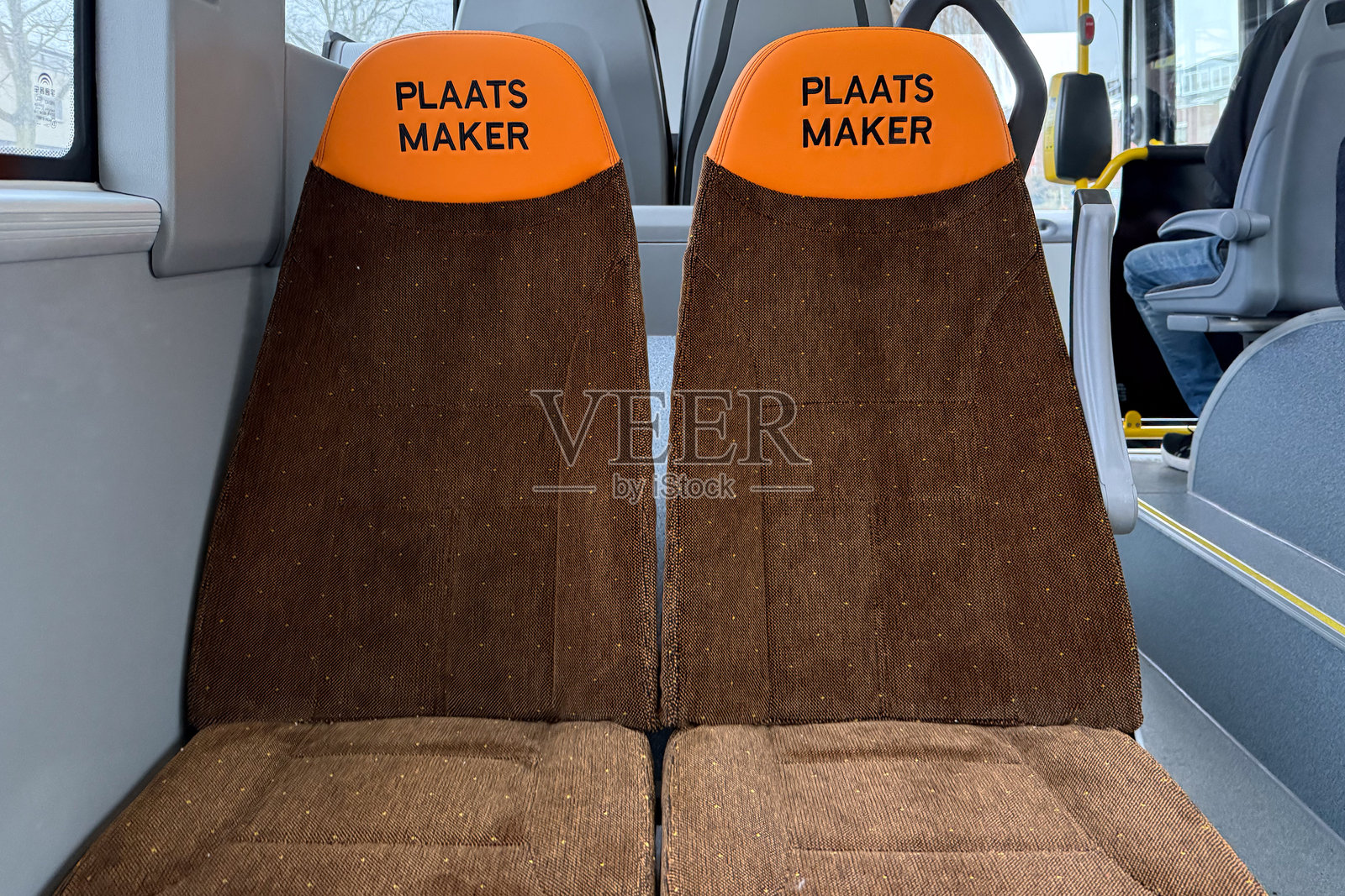 公交车座位上贴有荷兰语文字，请求为残疾人和老年乘客让座照片摄影图片