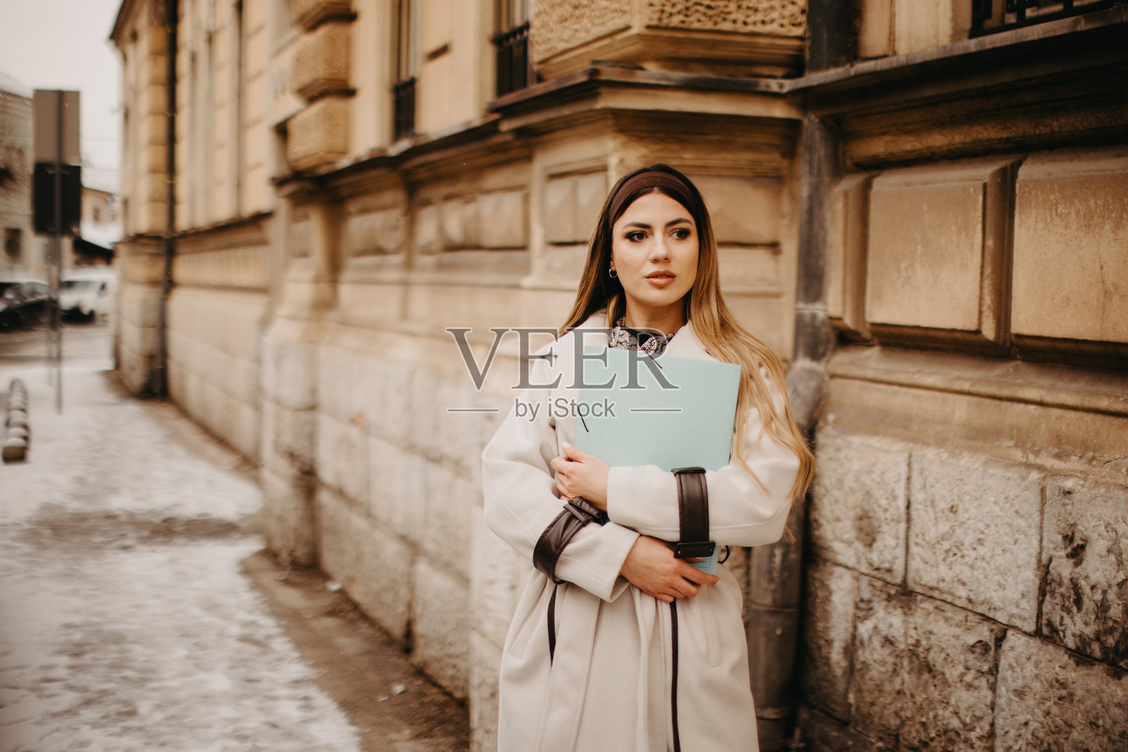 年轻女子走在城市街道上，手中拿着文件照片摄影图片