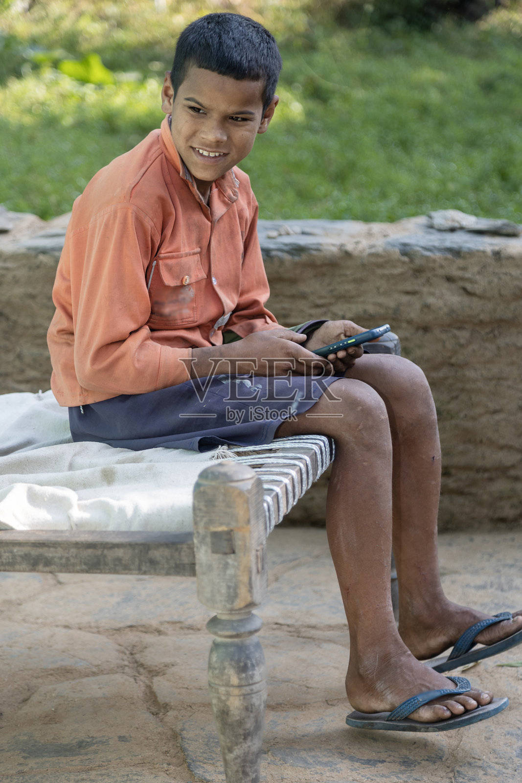 贫困的北阿坎德邦山区农家男孩在家中使用智能手机照片摄影图片