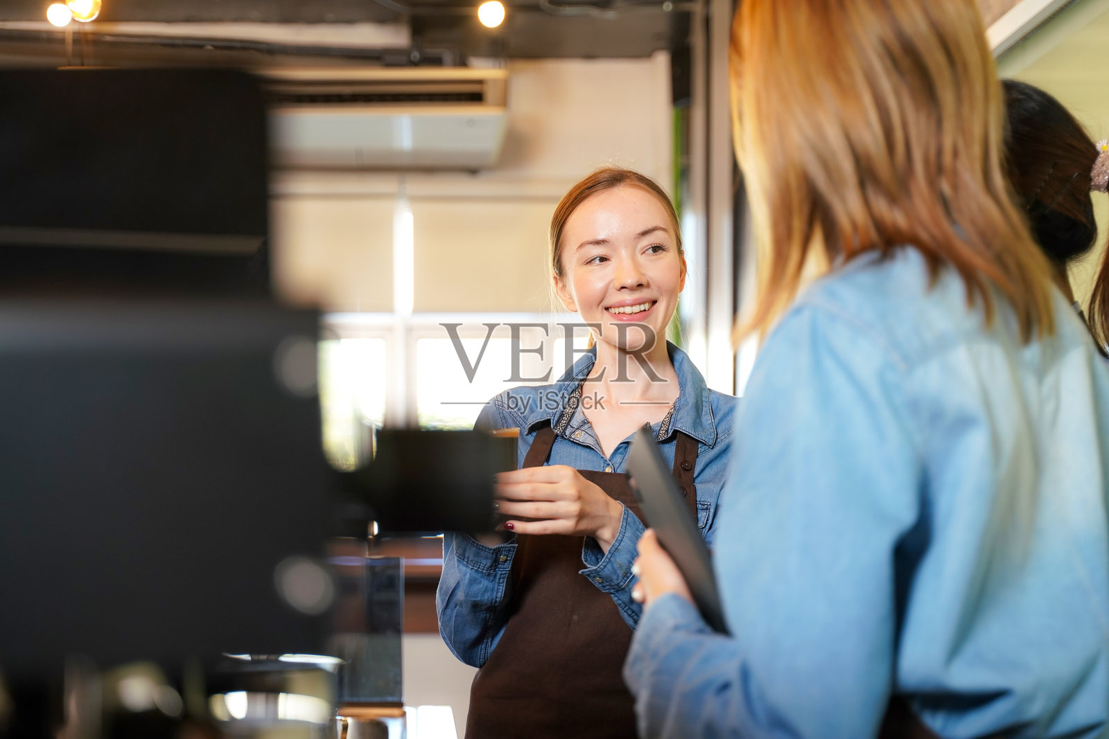 咖啡馆内，一群年轻女性参加咖啡师培训课程，围在一起学习。照片摄影图片