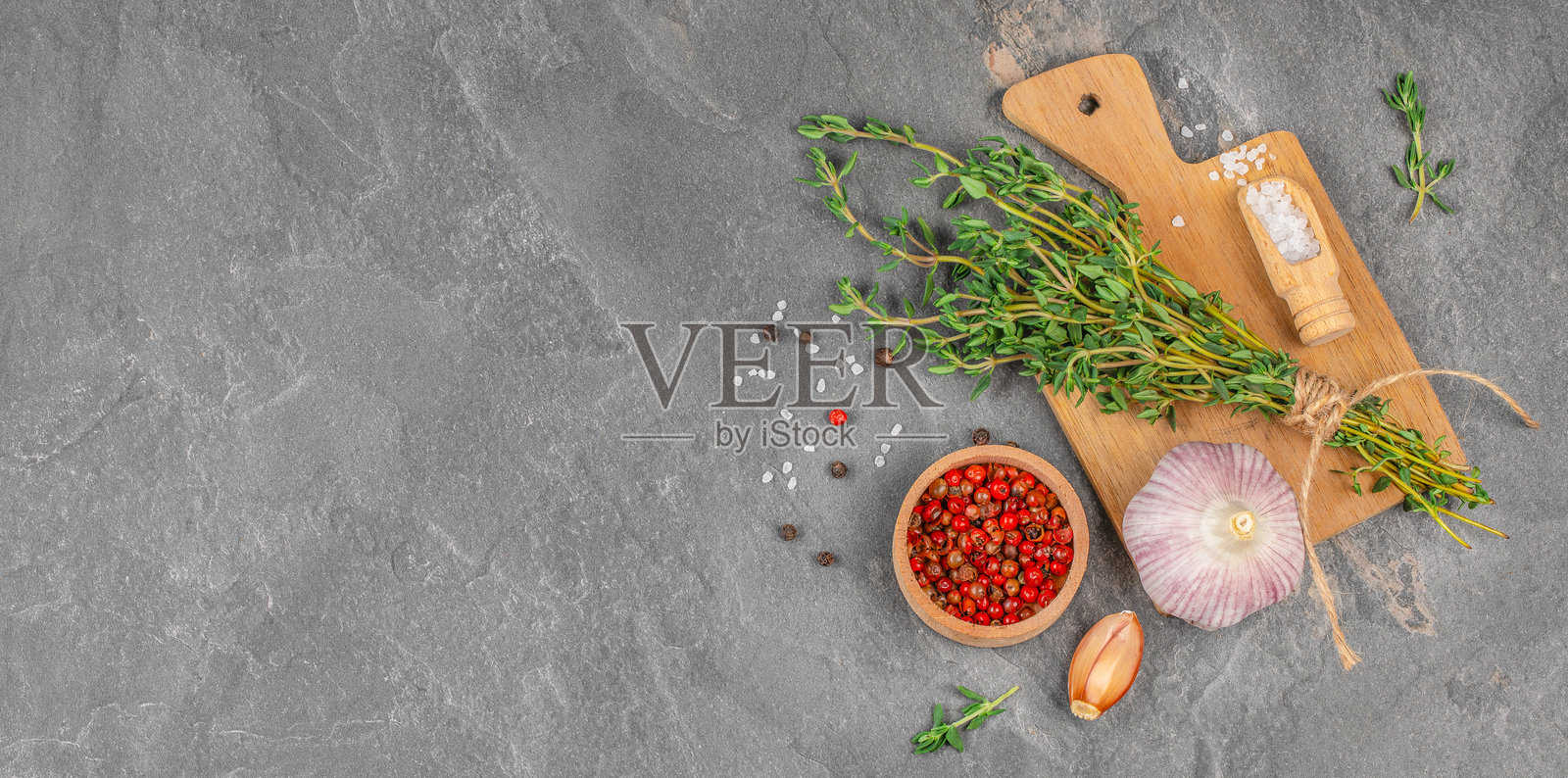 深色石材背景上的新鲜百里香、大蒜、海盐和胡椒照片摄影图片