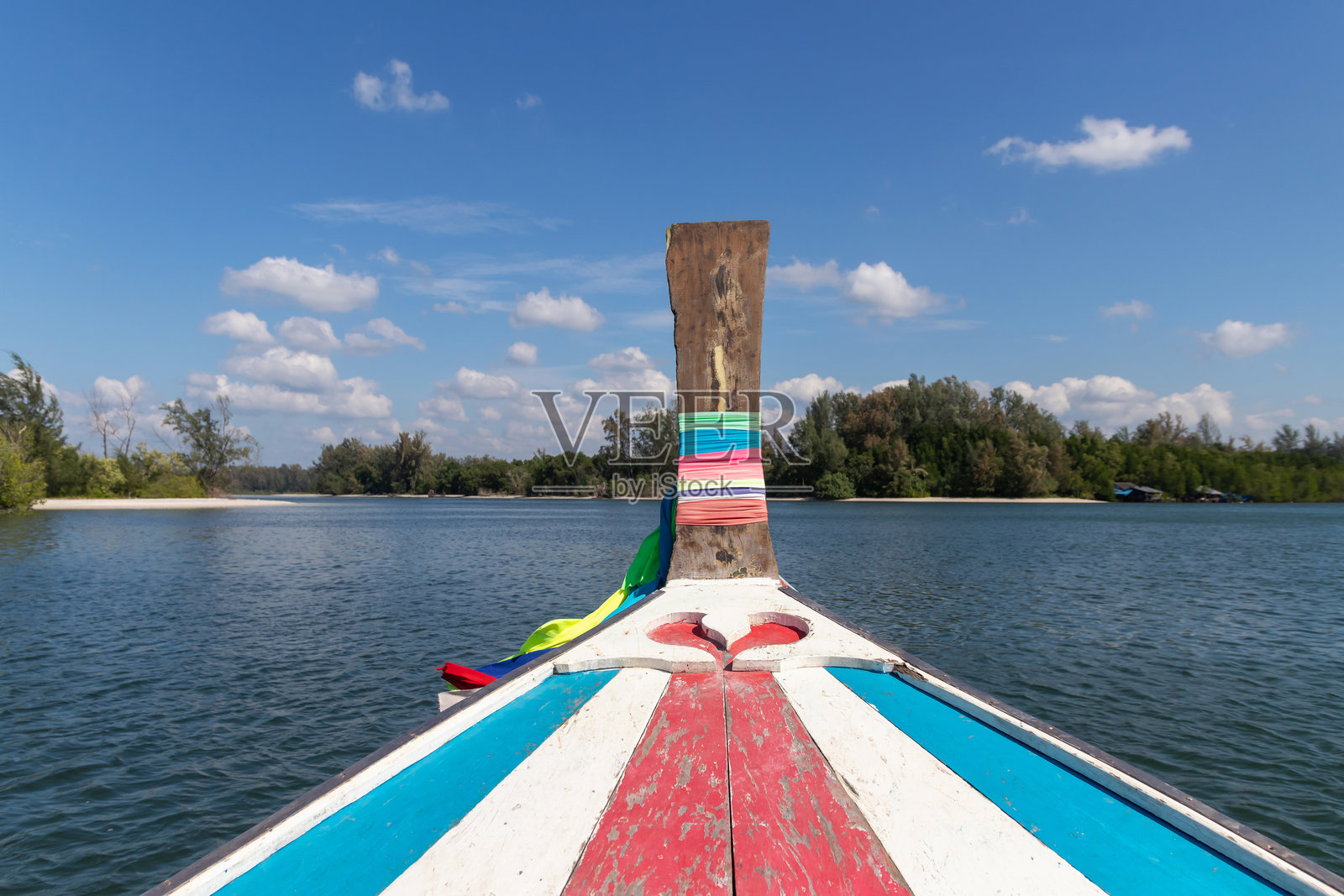 热带泻湖上色彩鲜艳的木制长尾船船头，背景是蓝天和树木，宁静的旅行场景照片摄影图片