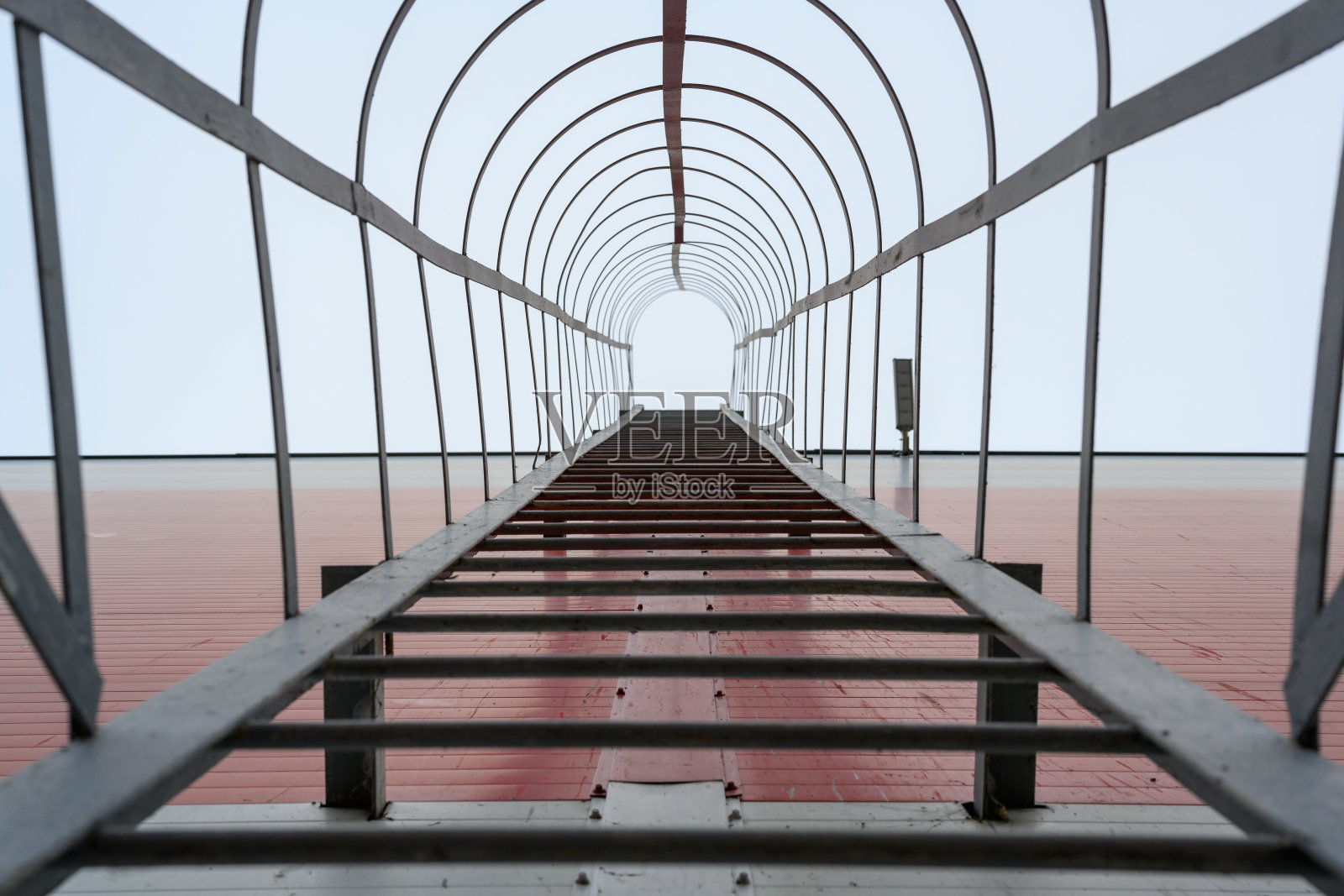 通过砖墙上的金属梯子攀爬向天空照片摄影图片