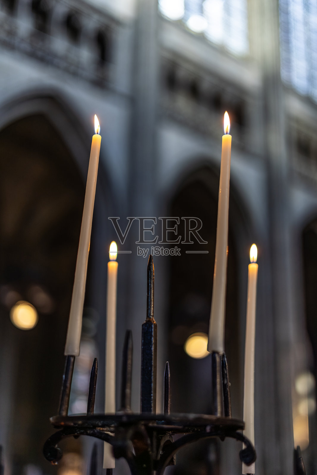 天主教堂内部的祭坛上燃烧的蜡烛。神圣信仰和祈祷的宗教象征，背景是模糊的哥特式建筑和彩色玻璃窗。照片摄影图片